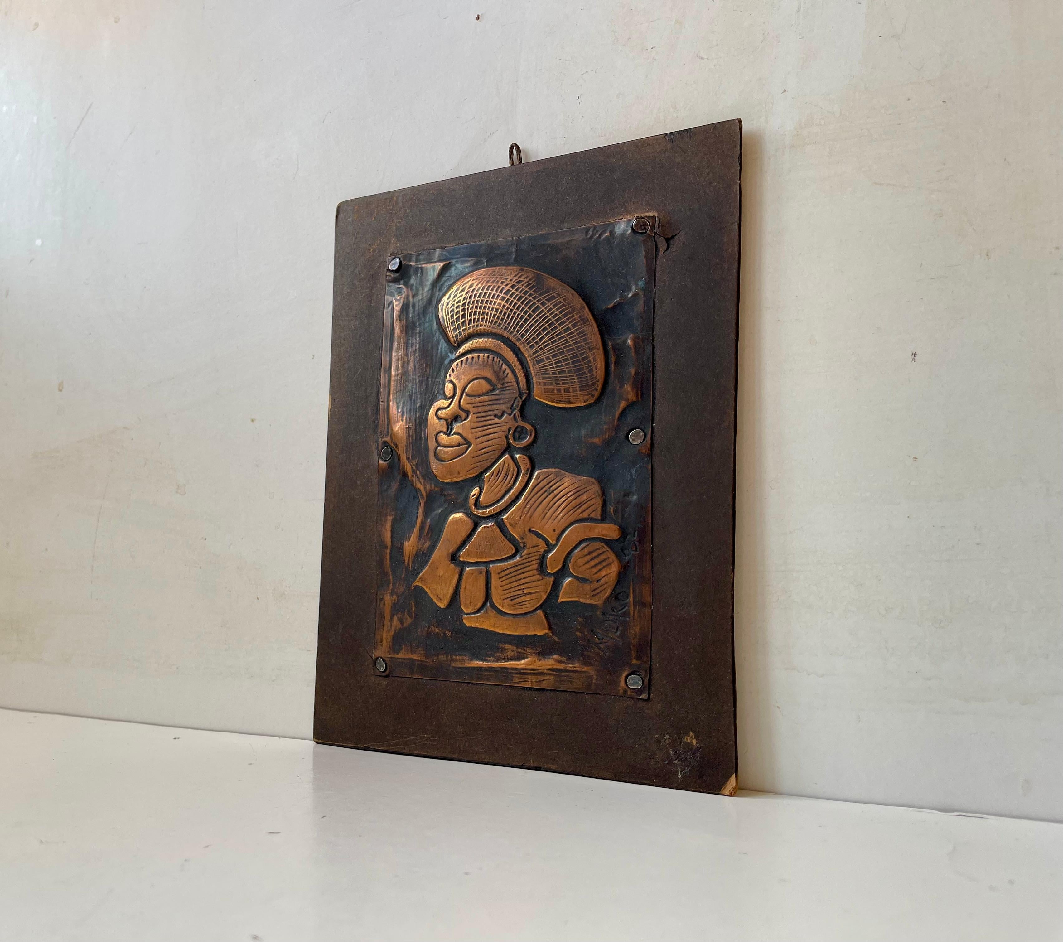 Hand-crafted embossed copper wall plaque depicting a tribe/traditional South African woman. Signed Muko and dated or numbered 82. Mounted on a wooden back-plate with nails. 

Measurements: 20x15x1 cm.