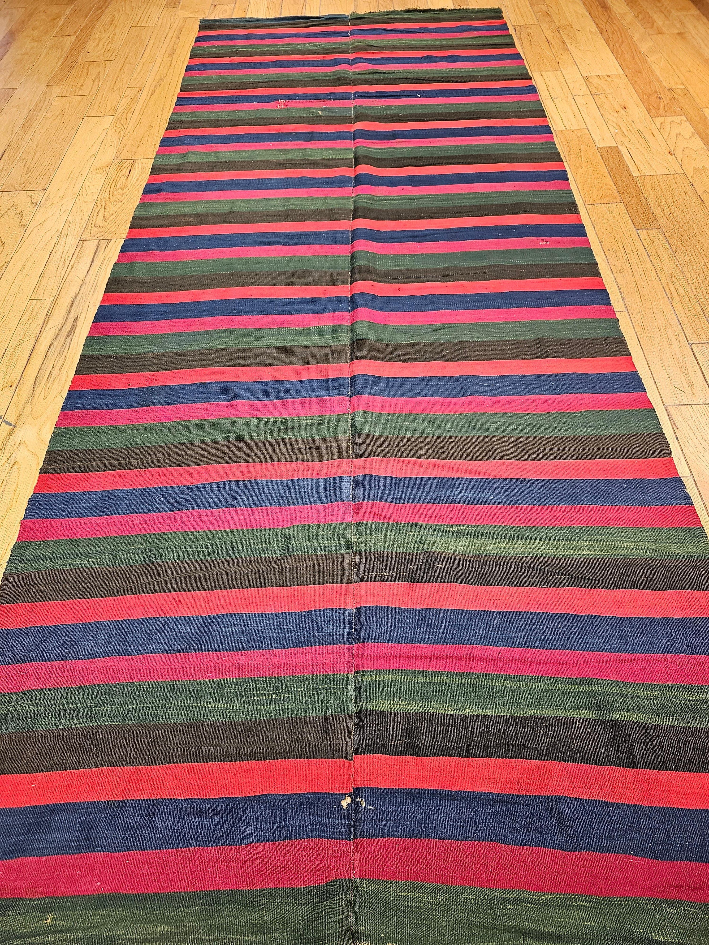 Beautiful vintage oversized South American kilim in a banded stripes design with brilliant stripes in colors of Blue, red, green, black, orange and magenta. The kilim has an extremely fine weave and a very high quality handspun wool that was hand
