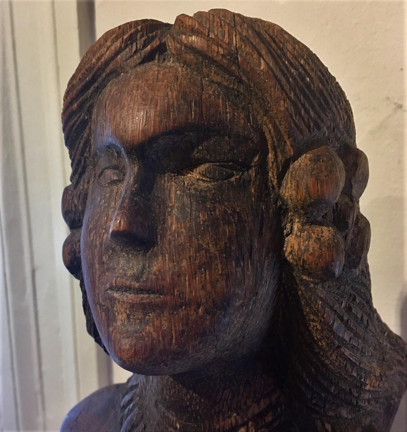 Early vintage or antique South Seas carved teak Mermaid, circa 1920s or perhaps earlier, a hand carved upright figure holding a carved shell, with deeply carved flowers in grooved hair flowing down back, shell necklace, and scale pattern throughout