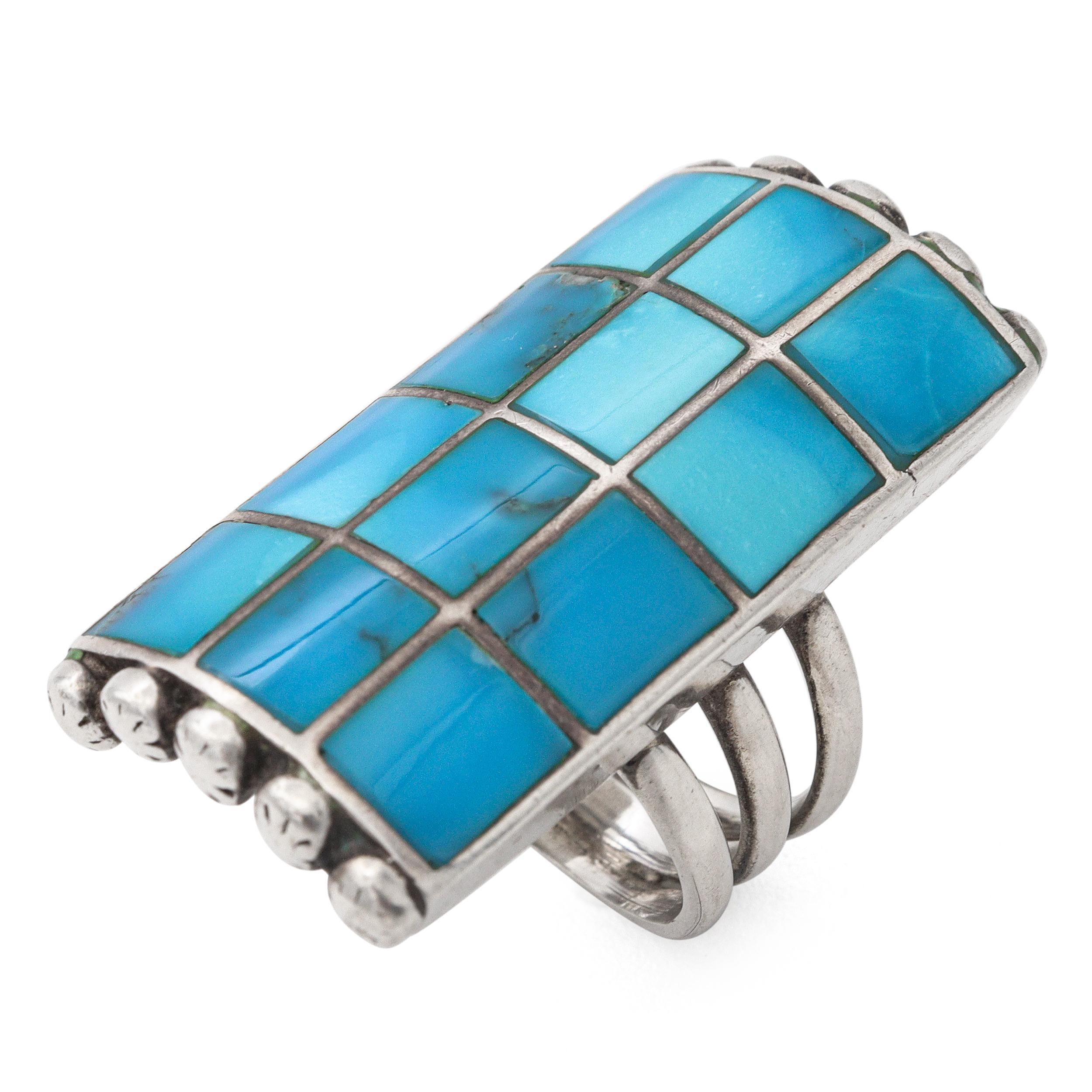 This bold sterling silver ring showcases a striking mosaic-style turquoise inlay design, crafted with precision and artistry. The elongated rectangular face is composed of hand-cut turquoise stones in varying shades of blue, each carefully set into
