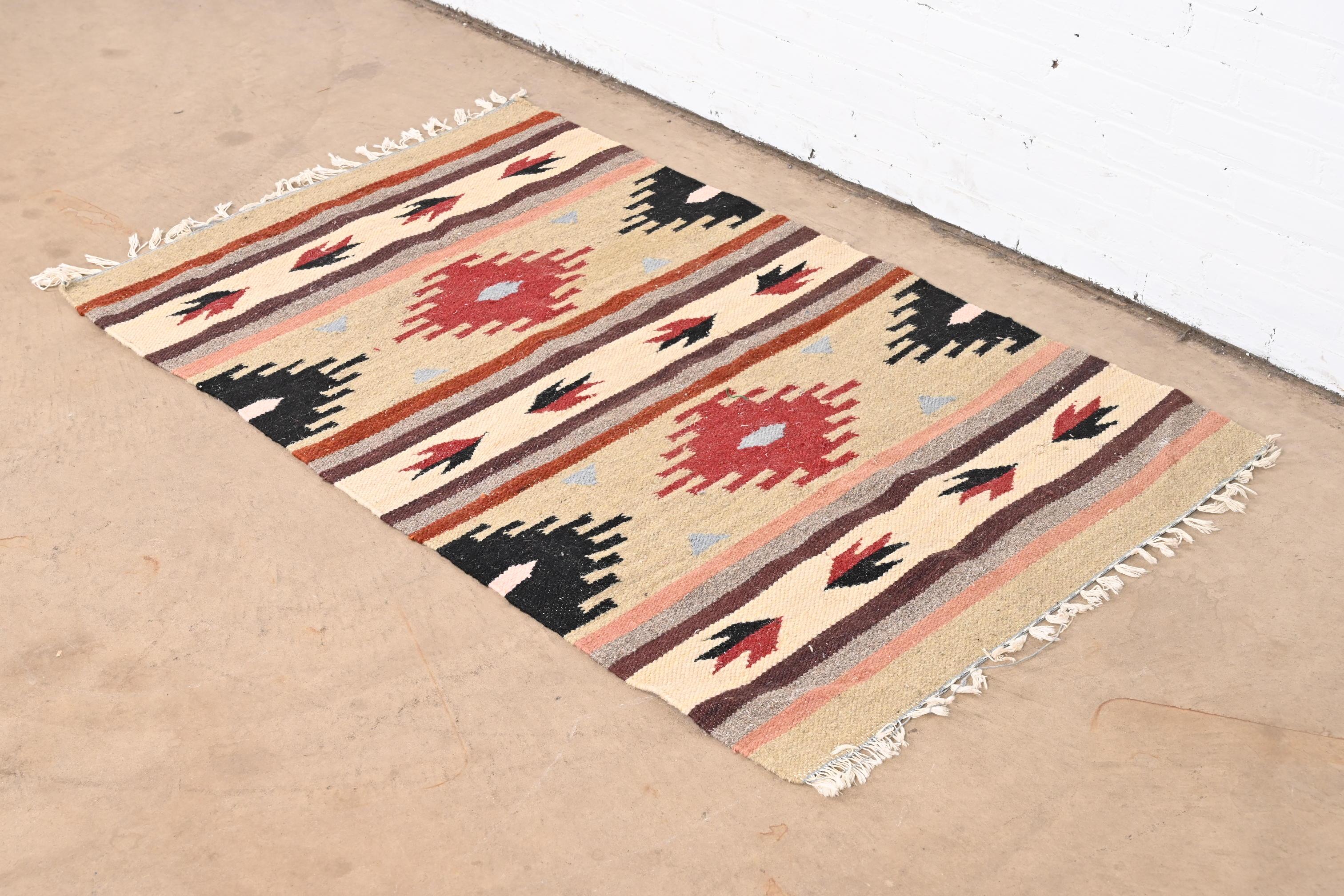A gorgeous vintage Southwest Navajo style flat weave rug

Late 20th century

Colorful and vibrant geometric design, with predominant colors in tan, red, black, and brown.

Measures: 35.5