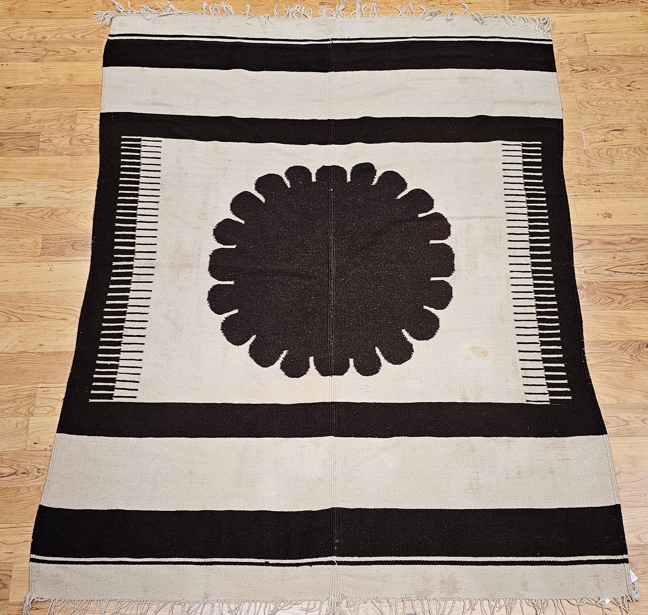 This vintage American Southwestern kilim area rug, crafted in the 20th century, showcases a warm, earthy palette of ivory and brown. Traditionally woven in two separate panels—a common method for larger kilims—this finely woven flat weave rug