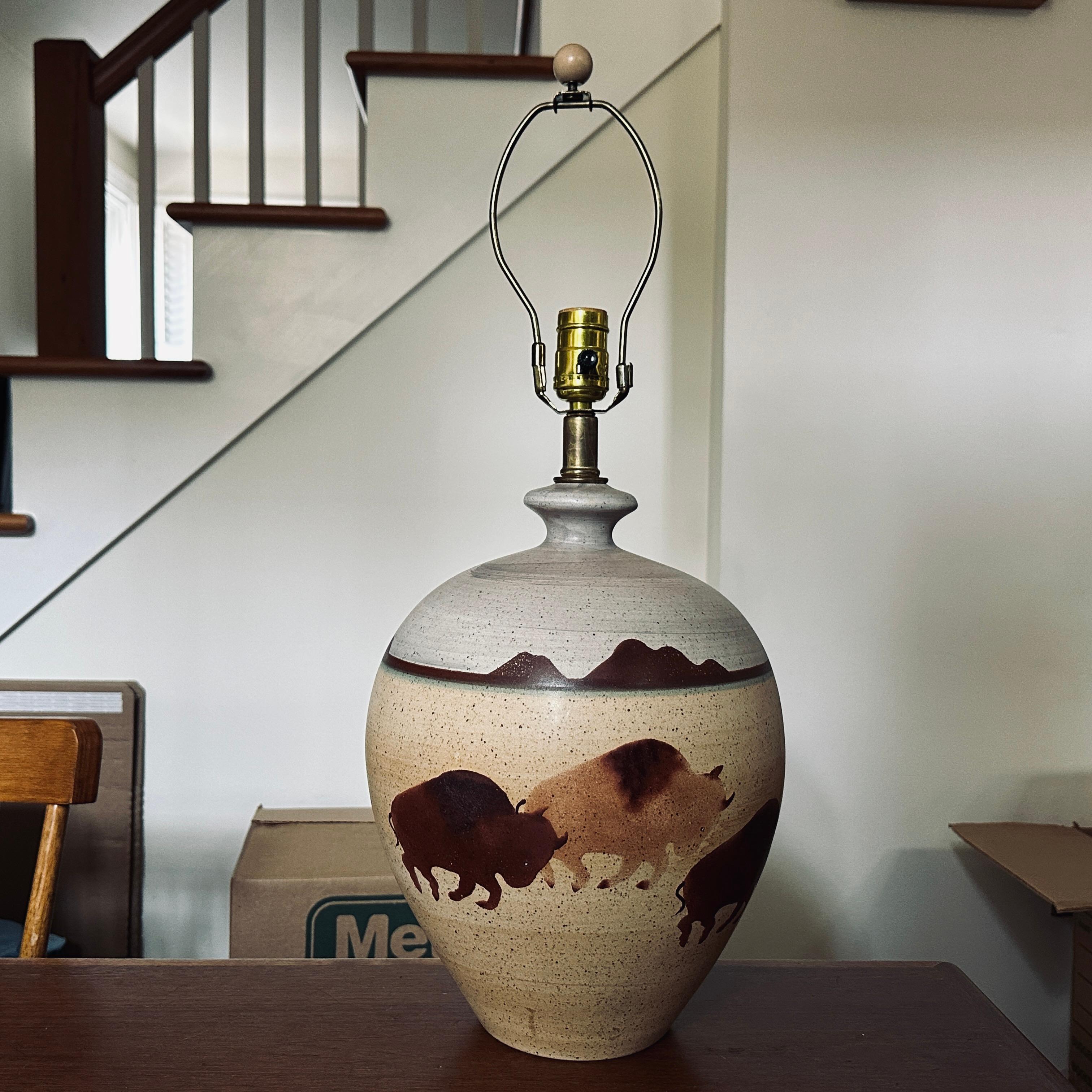 Vintage ceramic lamp by California Ceramic Designers Inc. featuring a Southwestern landscape around the circumference with three nicely detailed stampeding bison centered in the front. 
10