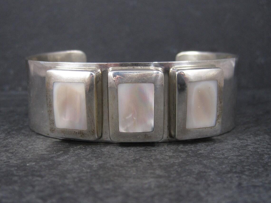 This gorgeous mother of pearl cuff bracelet is solid sterling silver.

This bracelet measures 7/8ths of an inch wide.
The inner dimensions measure 7 inches including a 1 1/2 inch gap.

It weighs 54.3 grams.

It is unmarked and unsigned.

Excellent