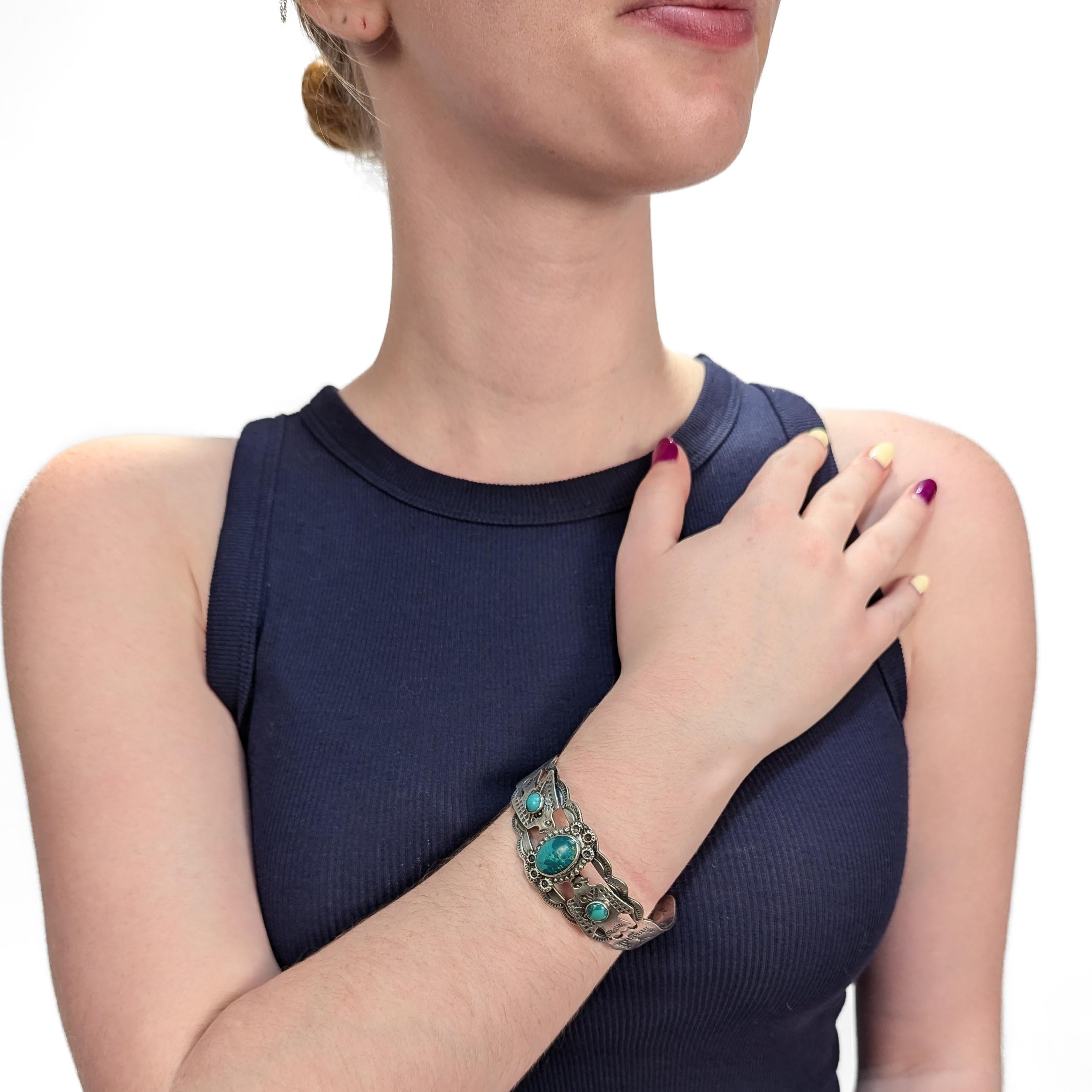 A fine Southwestern bracelet.

In sterling silver.

In the Navajo style.

With a central bezel-set turquoise cabochon flanked by two thunderbird devices with smaller cabochons. Decorated throughout with various hammered symbols and geometric