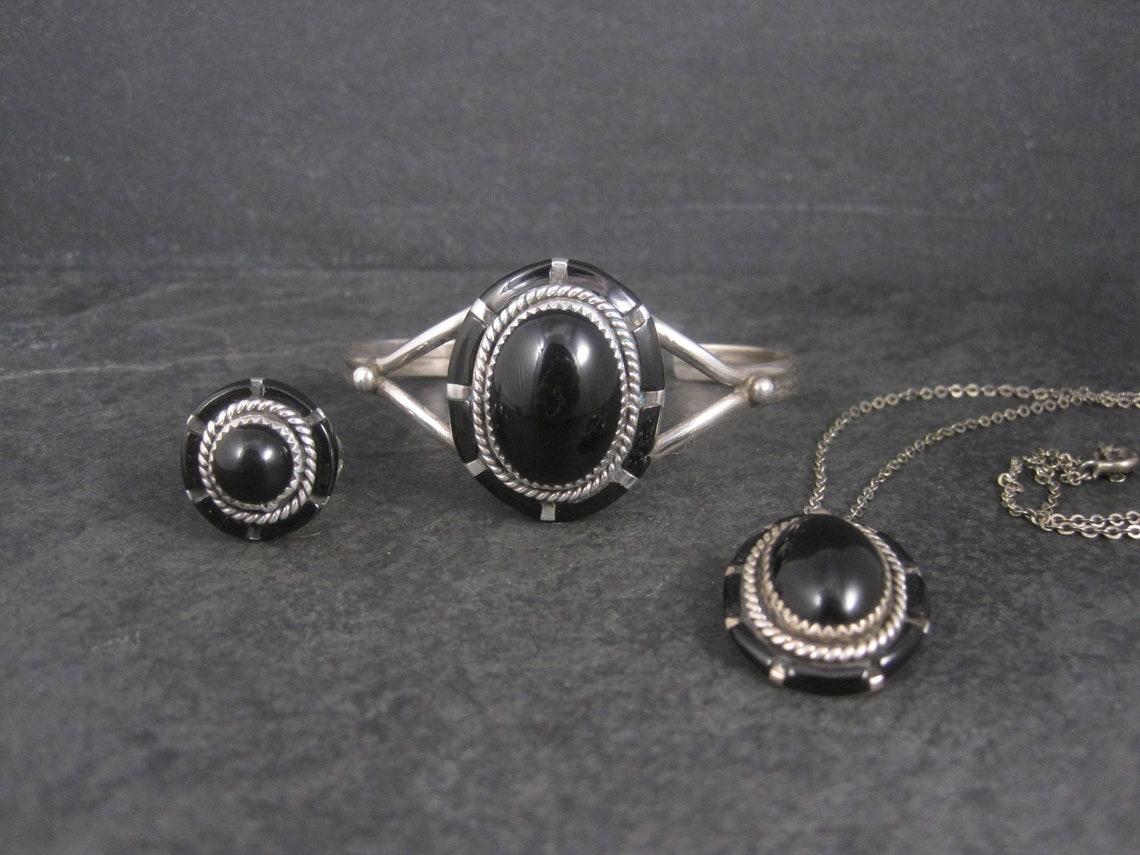 This beautiful southwestern jewelry set is sterling silver with onyx inlay.

Ring:
Size 5
The face of this ring measures 3/4 of an inch north to south with a rise of 8mm off the finger.
Marks: Sterling
Weight: 5.6 grams
Condition: