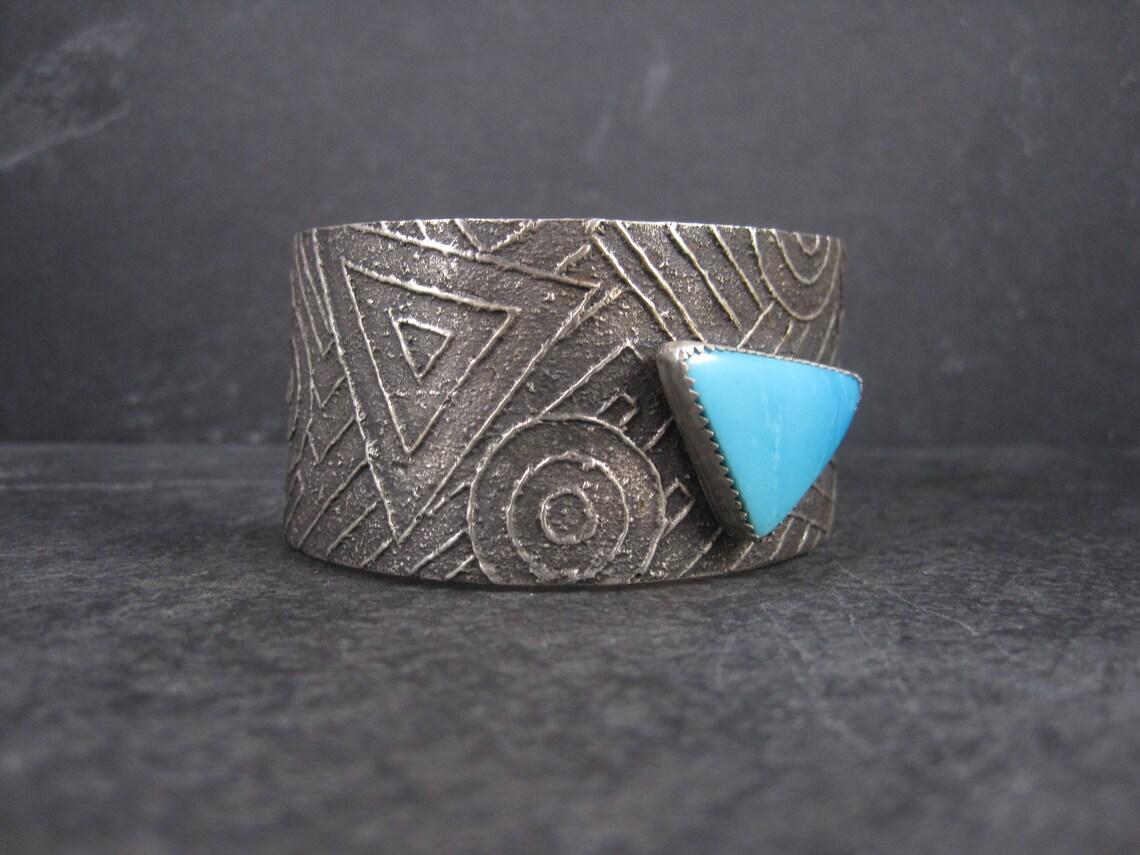 This beautiful, vintage tufa cast cuff bracelet is sterling silver.
It features a 17x25mm turquoise gemstone.

This bracelet measures 1 1/4 inches wide.
It has an inner circumference of 7 inches, including the 1 1/4 inch gap.
Weight: 82.3