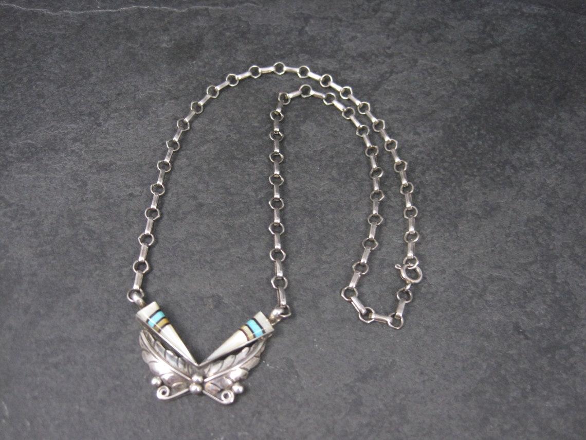 This gorgeous Southwestern necklace is sterling silver.
It features turquoise and mother of pearl inlay.

The pendant on this necklace measures 1 5/8 by 1 1/16 inches.
The necklace measures 18 1/2 inches from end to end.

Marks: None

Condition: