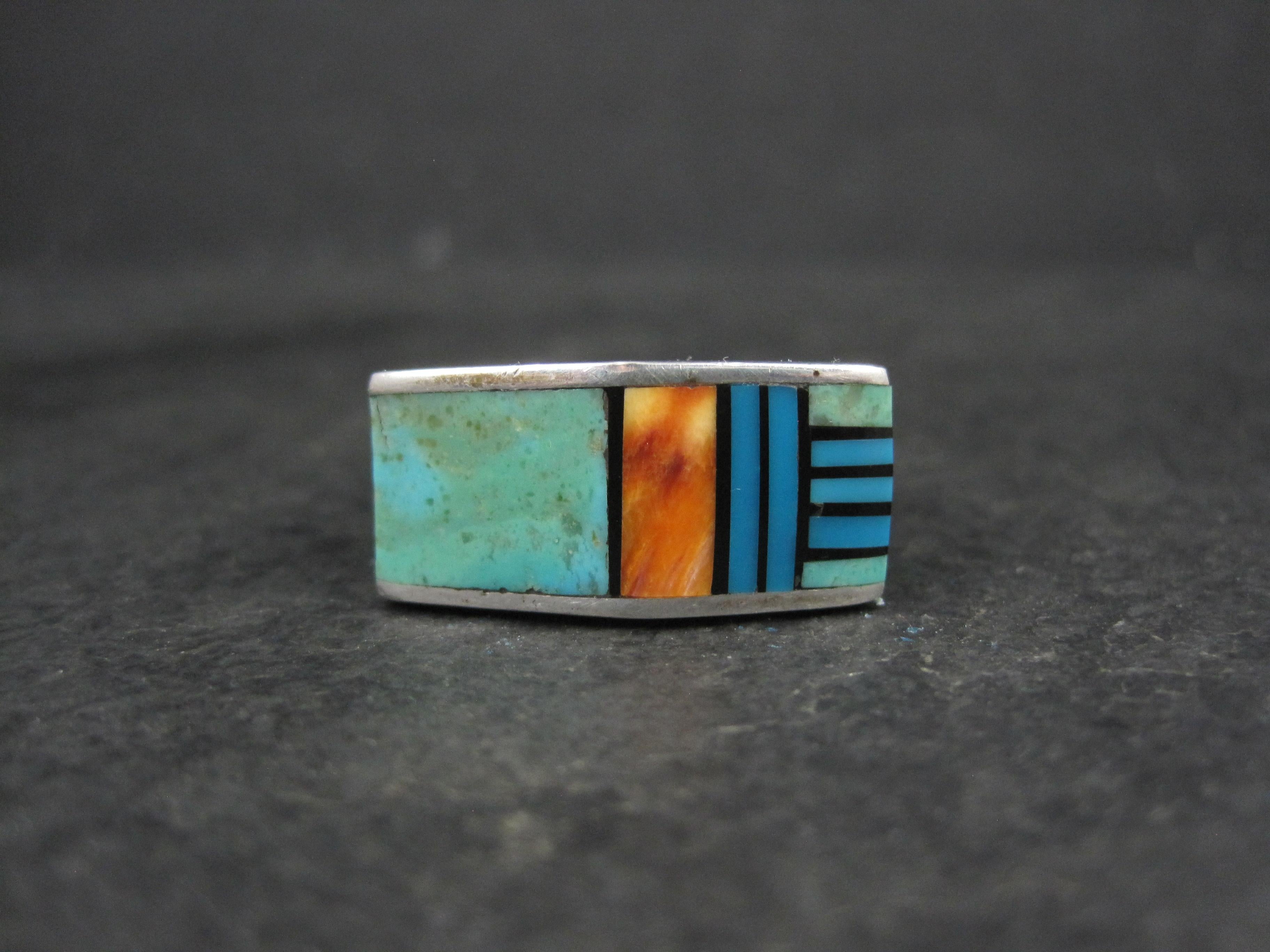 This gorgeous, vintage Southwestern ring is sterling silver with a combination of turquoise, spiny oyster and jet inlay. 
The face of this ring measures 7/16 of an inch north to south, 1 inch east to west and has a rise of 8mm off the finger.
Size: