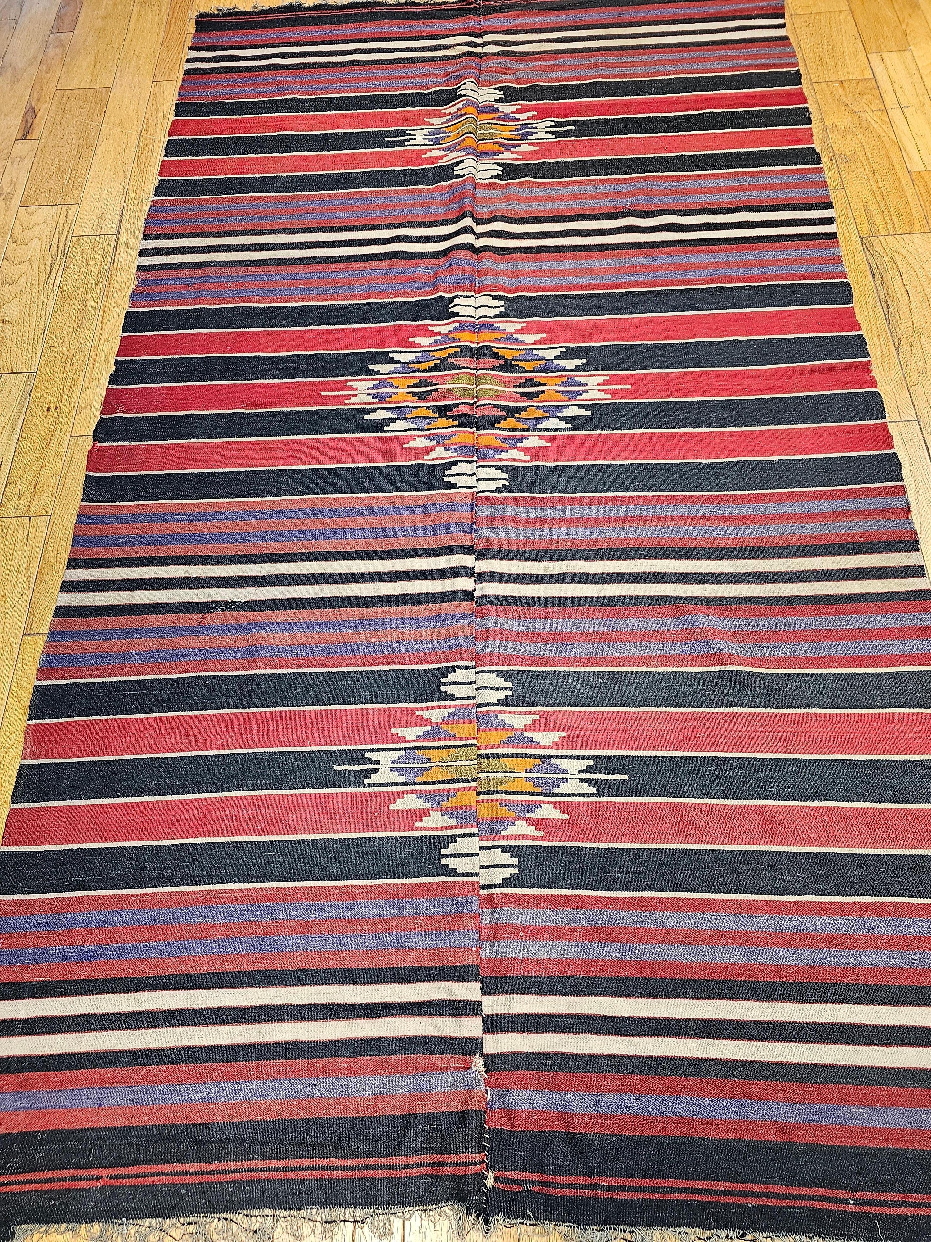 A beautiful mid century modern hand woven kilim with a stripe pattern and three small medallions.  The colors in the kilim including red, lavender, orange, and ivory represent the colors in the American Southwest landscape of mountains and canyons