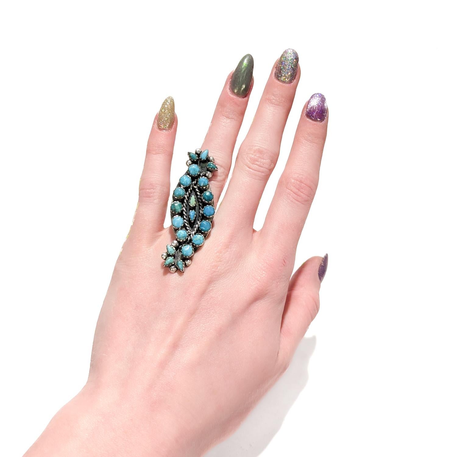 A fine vintage Native American silver & turquoise ring.

Made of solid silver (we assume sterling).

Set with 20 turquoise cabochons (either circular or triangular) in a pattern reminiscent of plants or flowers.

Simply a wonderful Southwestern