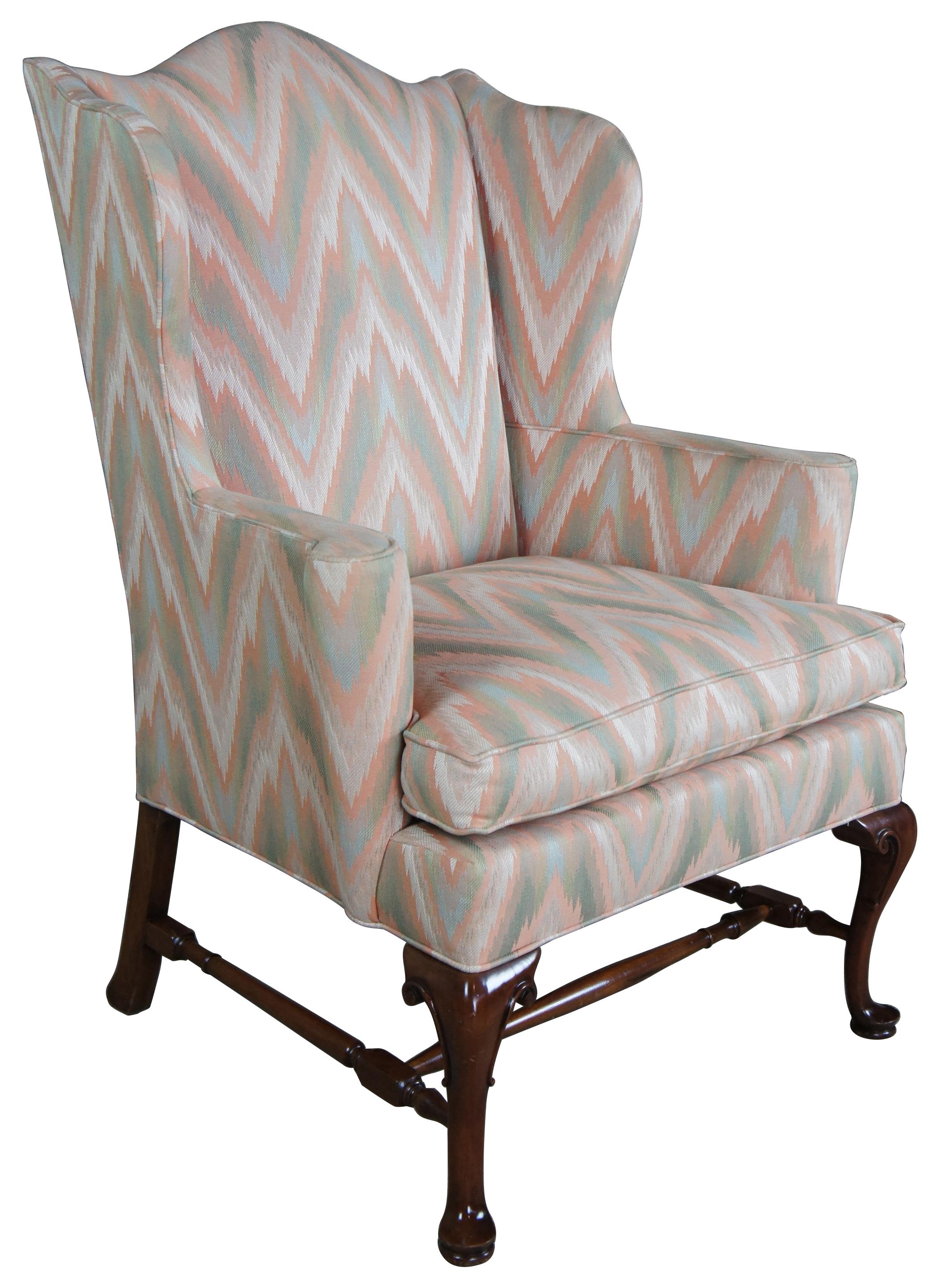 Southwood (Hickory, North Carolina) wingback chair. Made from mahogany frame with carved cabriole legs in front and square splayed legs at back. Lets are connected by a turned H-stretcher, upholstered in a pink green and white zigzag fabric.
       