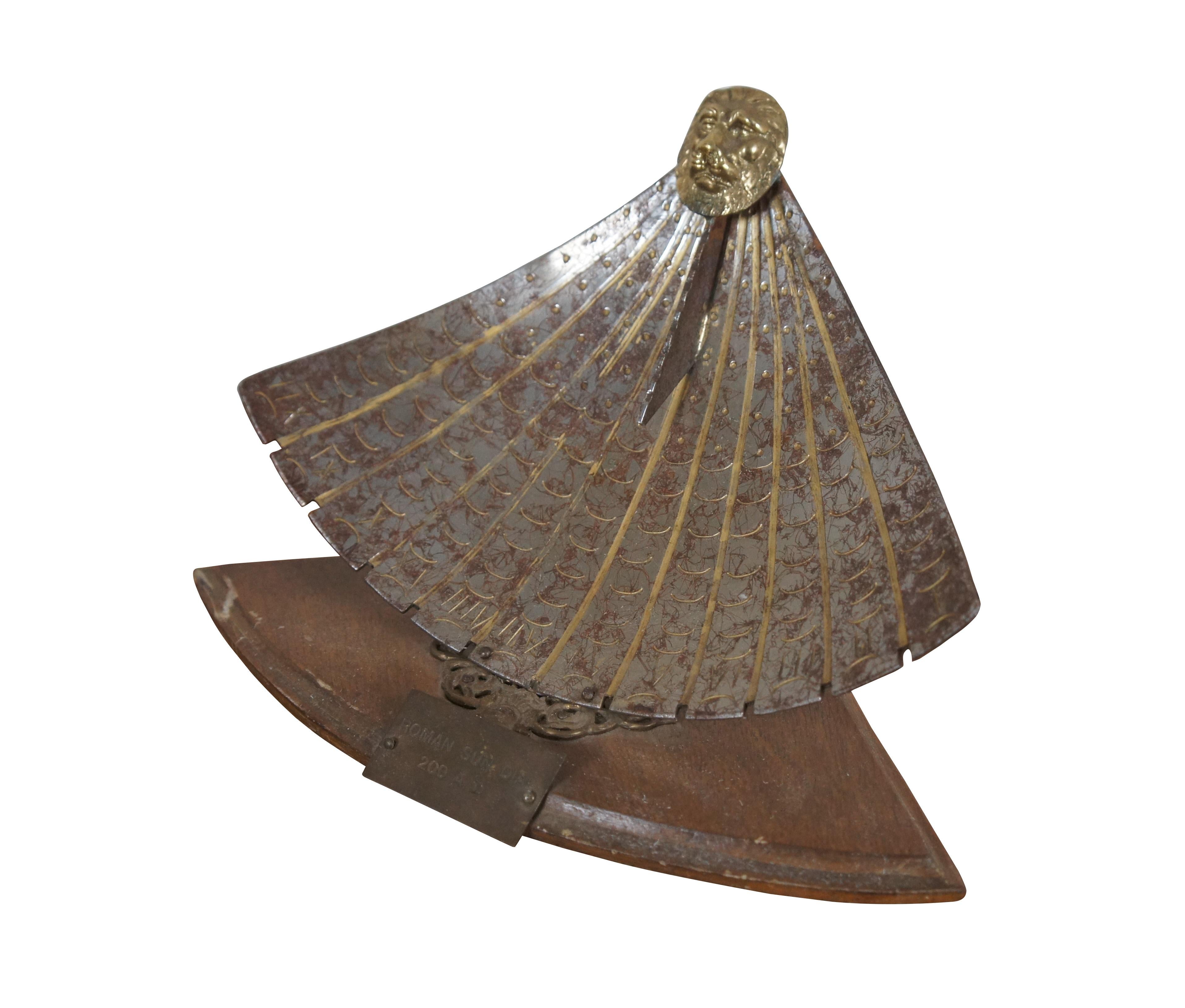 Mid 20th century sounvenir reproduction of an ancient Roman sun dial. Fan shaped metal dial plate, decoratively aged, with etched / gilded rays and Roman numerals indicating the hours, gnomon capped with a gilt lion's head. Mounted on a fan shape