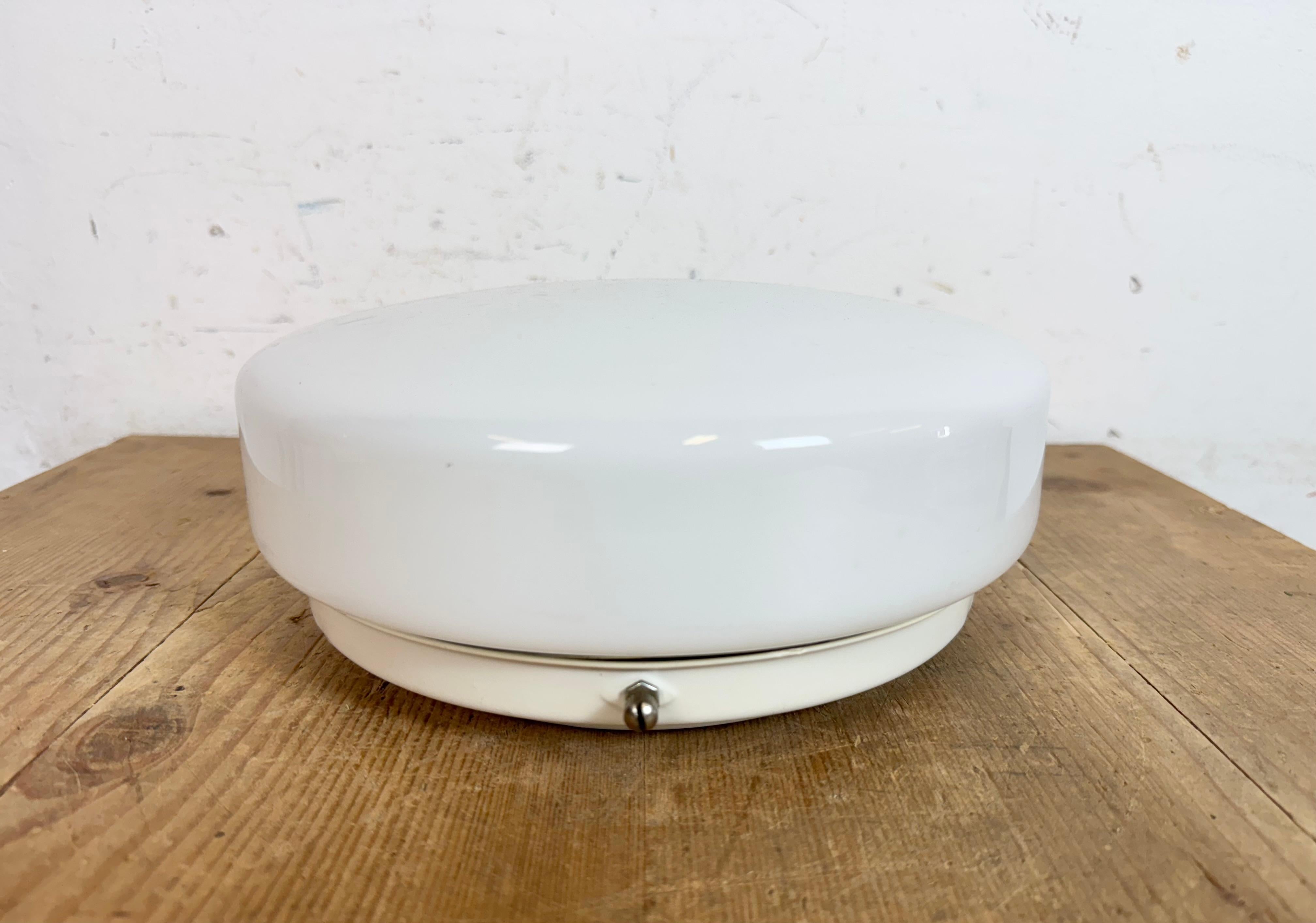 Plafón o aplique industrial vintage  Fabricado en la antigua Unión Soviética durante la década de los 80. Presenta una montura de pared o techo de hierro blanco y una cubierta de cristal de leche. El casquillo requiere bombillas estándar E27/E 26.