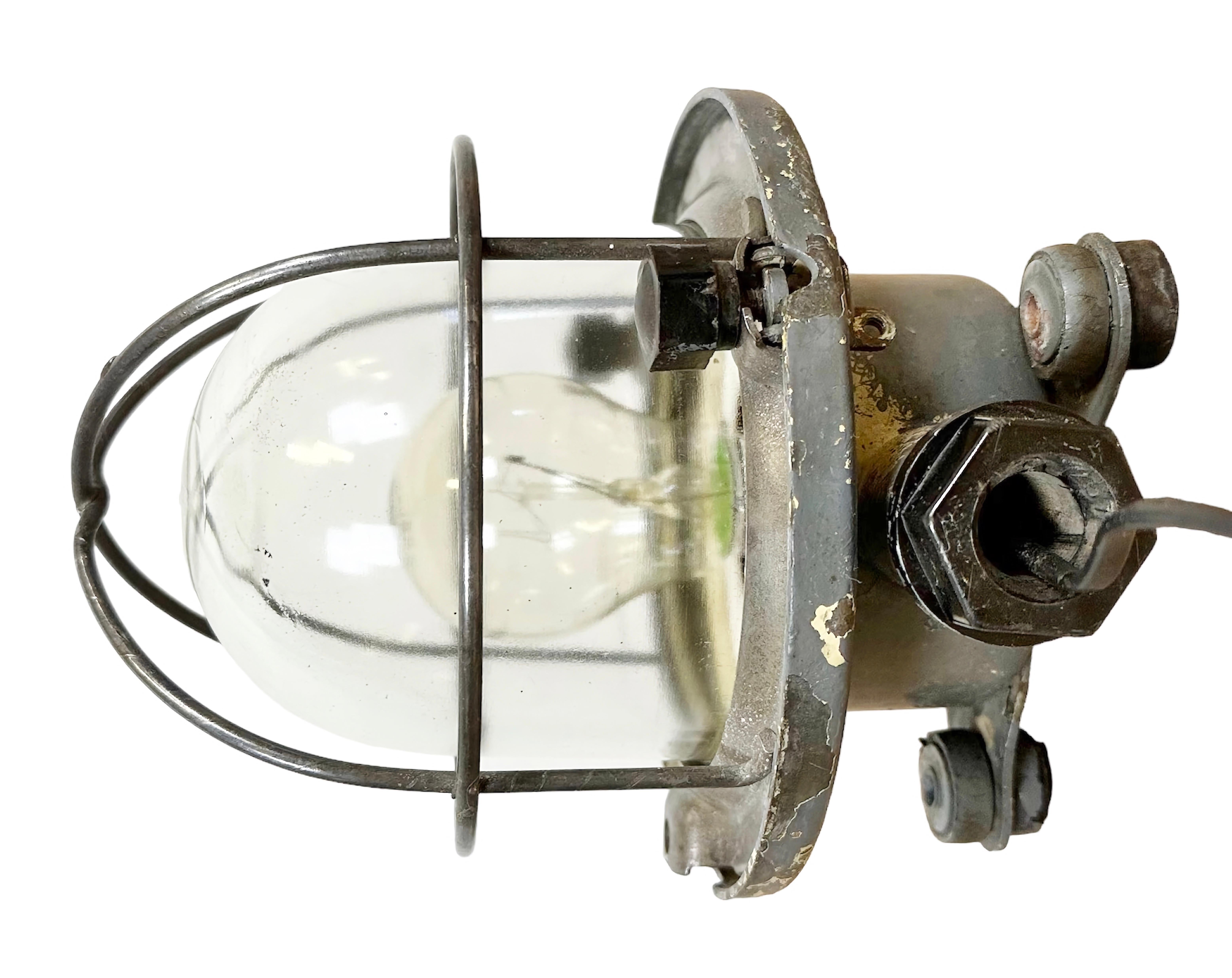 Vintage industrial celing or wall light made in former Soviet Union during the 1960s. It features a metal body with grid and a clear glass cover. The socket requires E 27/ E 26 light bulbs. New wire. The diameter of the lamp is 17cm. The weight of