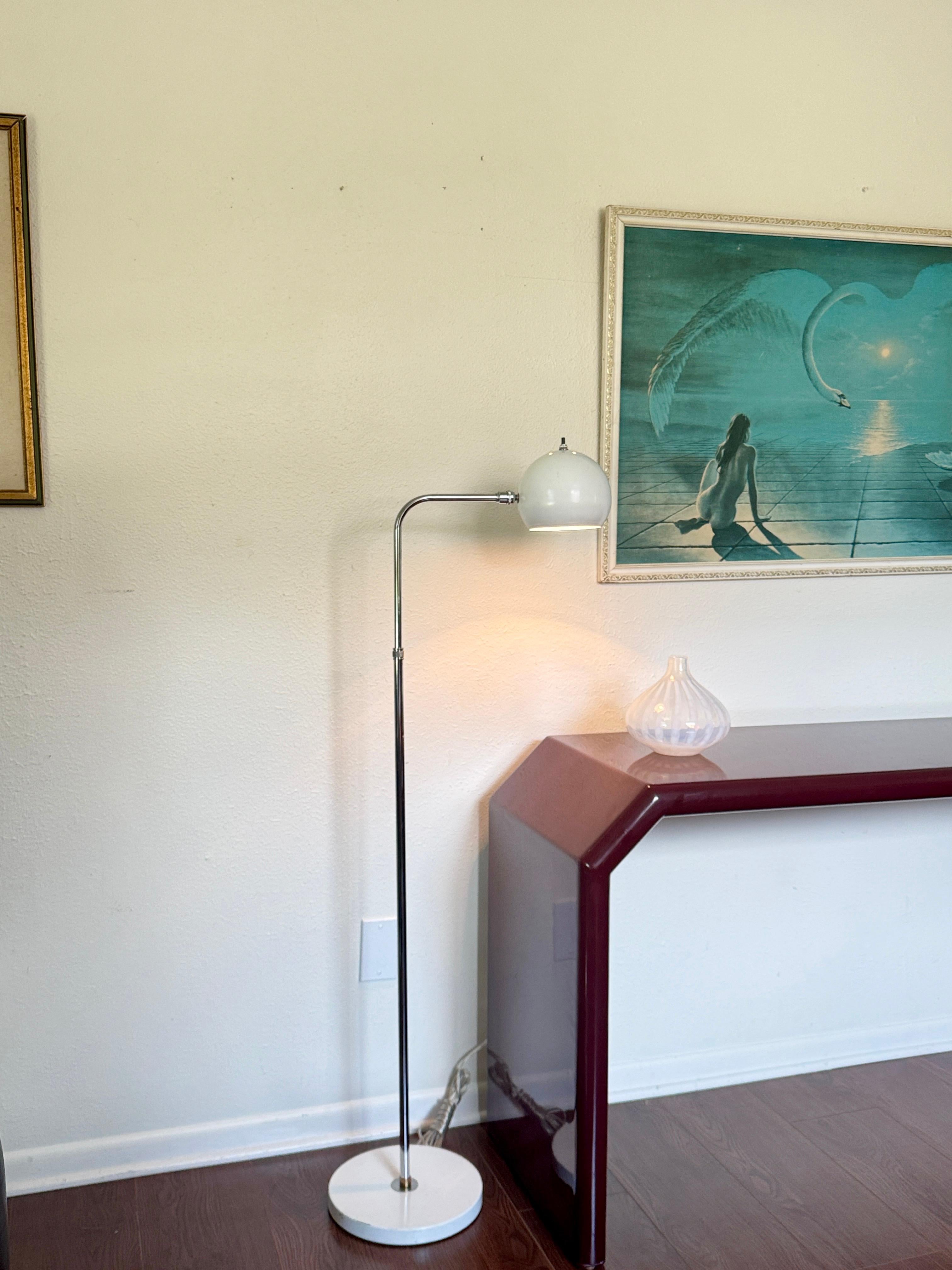 Vintage space age adjustable chrome floor lamp with white accents, circa 1970s. A striking example of mid century futurism, this adjustable chrome floor lamp features a glossy white base and a matching spherical “eyeball” shade that rotates to