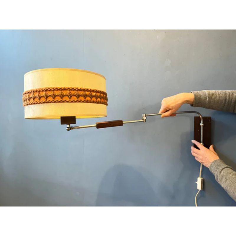 Classy mid-century wall lamp with textile shade and wooden elements. The lamp has a beige textile shade and the arm consists of metal and wood. The lamp requires an E27 (standard) lightbulb and currently has an EU-plug.

Dimensions:
ø Shades: 32