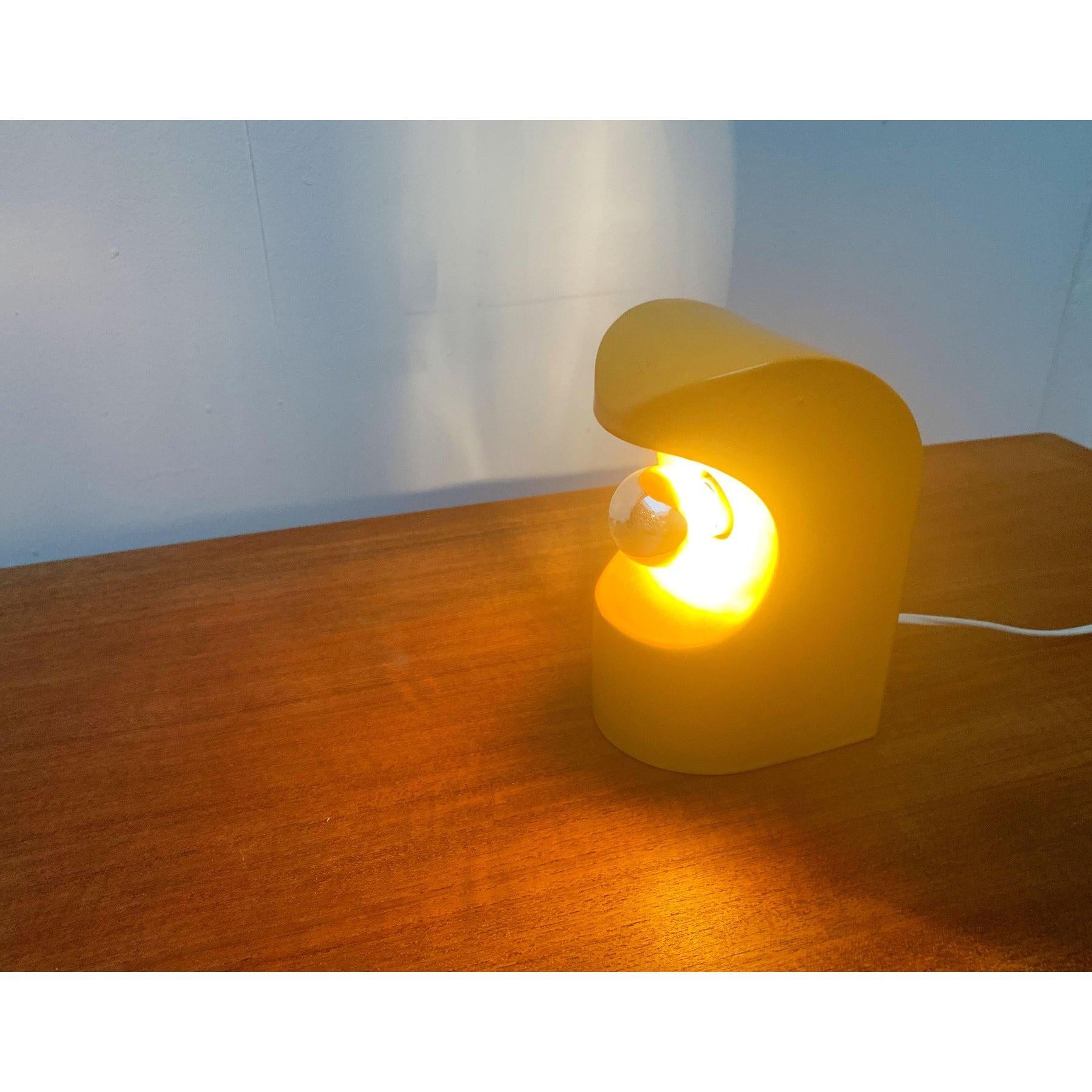 Lampe de table en céramique NO AGE.

Le corps complet du luminaire est conçu en céramique et émaillé dans un ton jaune foncé. L'avant est arrondi, l'arrière est carré. La face avant présente un large renfoncement rond, au centre duquel se trouvent
