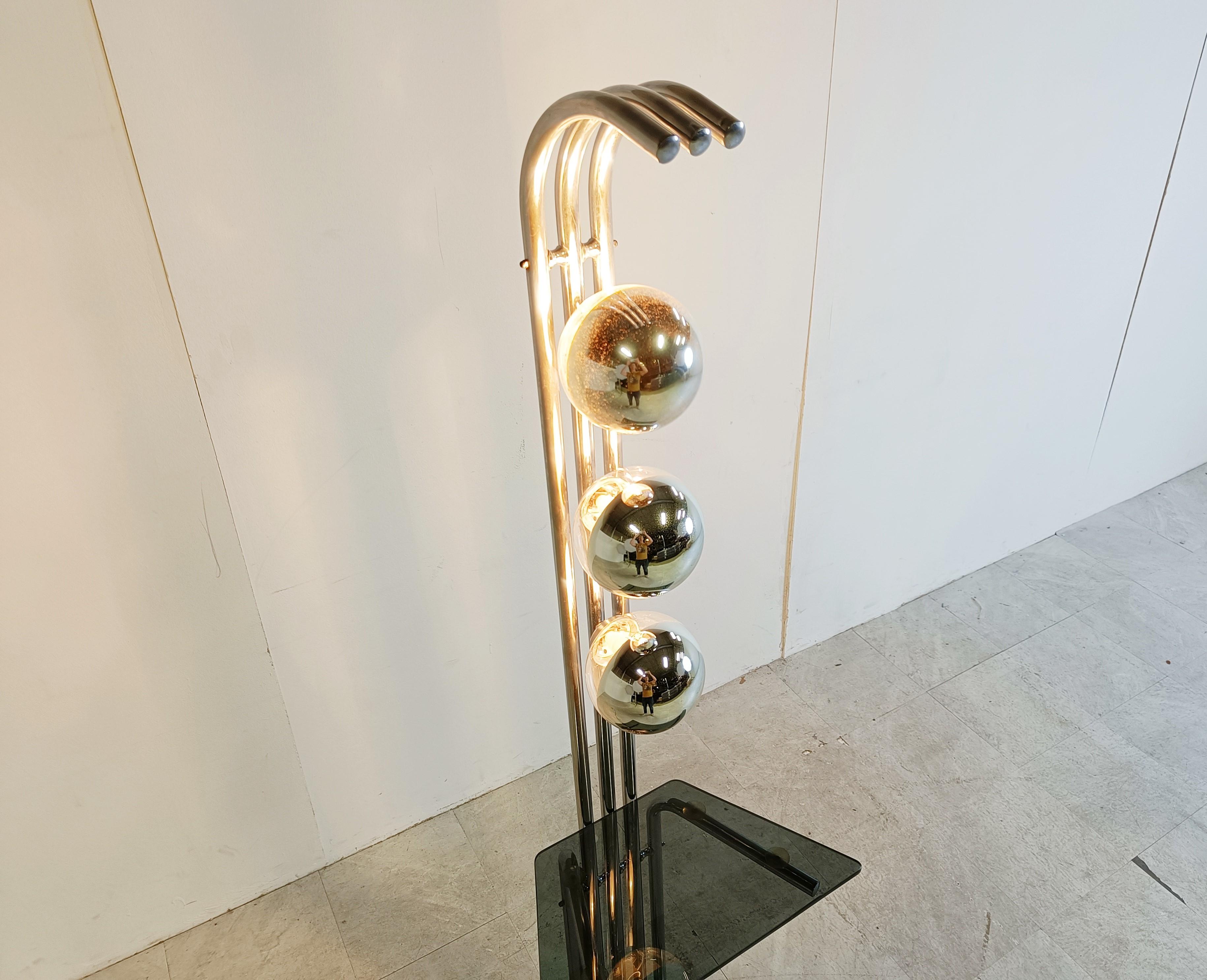 Mid century chromed floor lamp with 3 glass reflective glass globes and a smoked glass shelf.

The lamp has a nice space age vibe.

Good condition, tested and ready to use with 3 E14 light bulbs

1970s - Italy

Height: 168cm/66.14
