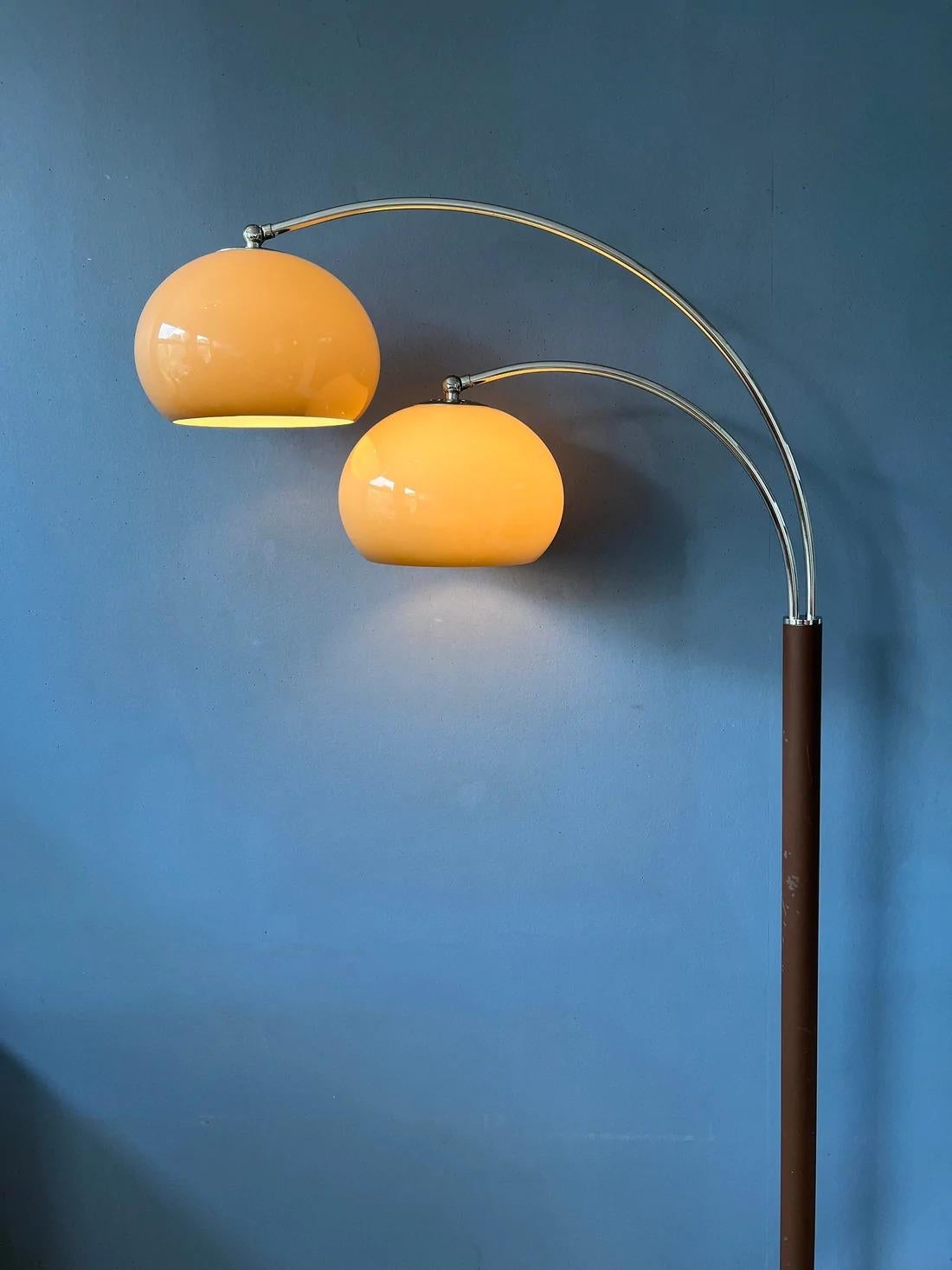 Lampadaire iconique Dijkstra à double arc avec des abat-jours champignons en verre acrylique de couleur beige et une base marron/chrome. Les abat-jours produisent une lumière chaude et peuvent être tournés vers le bas ou vers le haut. Les arcs sont
