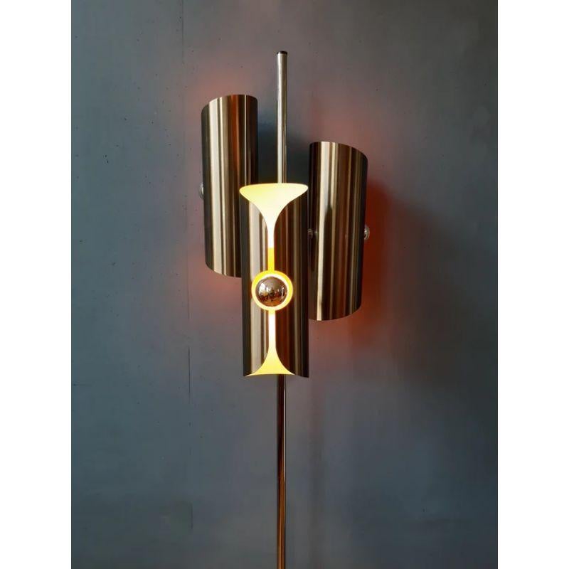 A very rare space age floorlamp often attributed to Raak but produced by the Polish company Polam. The floorlamp has a chrome frame and 3 pleated sleeves in brushed stainless steel with a partial yellow/orange interior. The lamp comes into its own