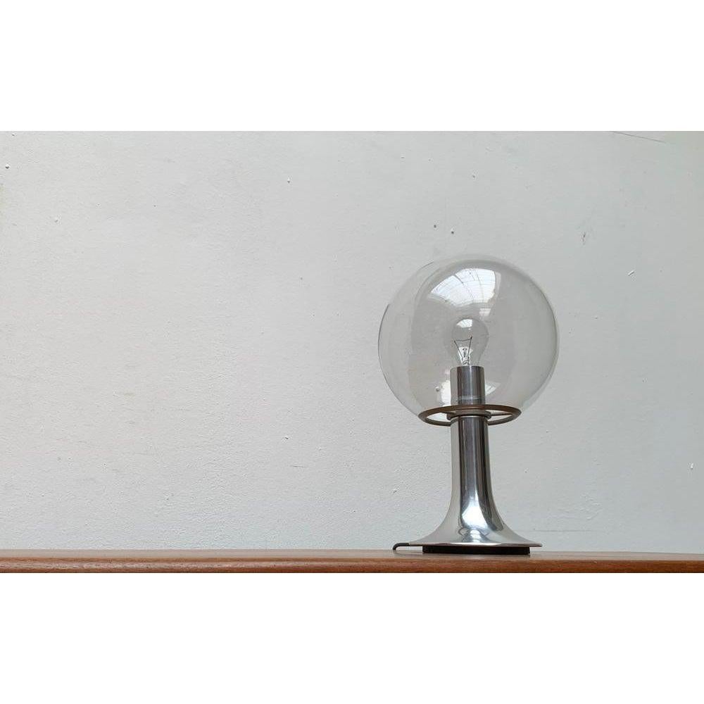 Imposante lampe de table Globe de l'ère spatiale.

La grande boule réflectrice est en verre transparent. Il convient dans un enregistrement annulaire, qui est relié au pied par trois fines bandes. L'ouverture vers le bas qui en résulte est utilisée
