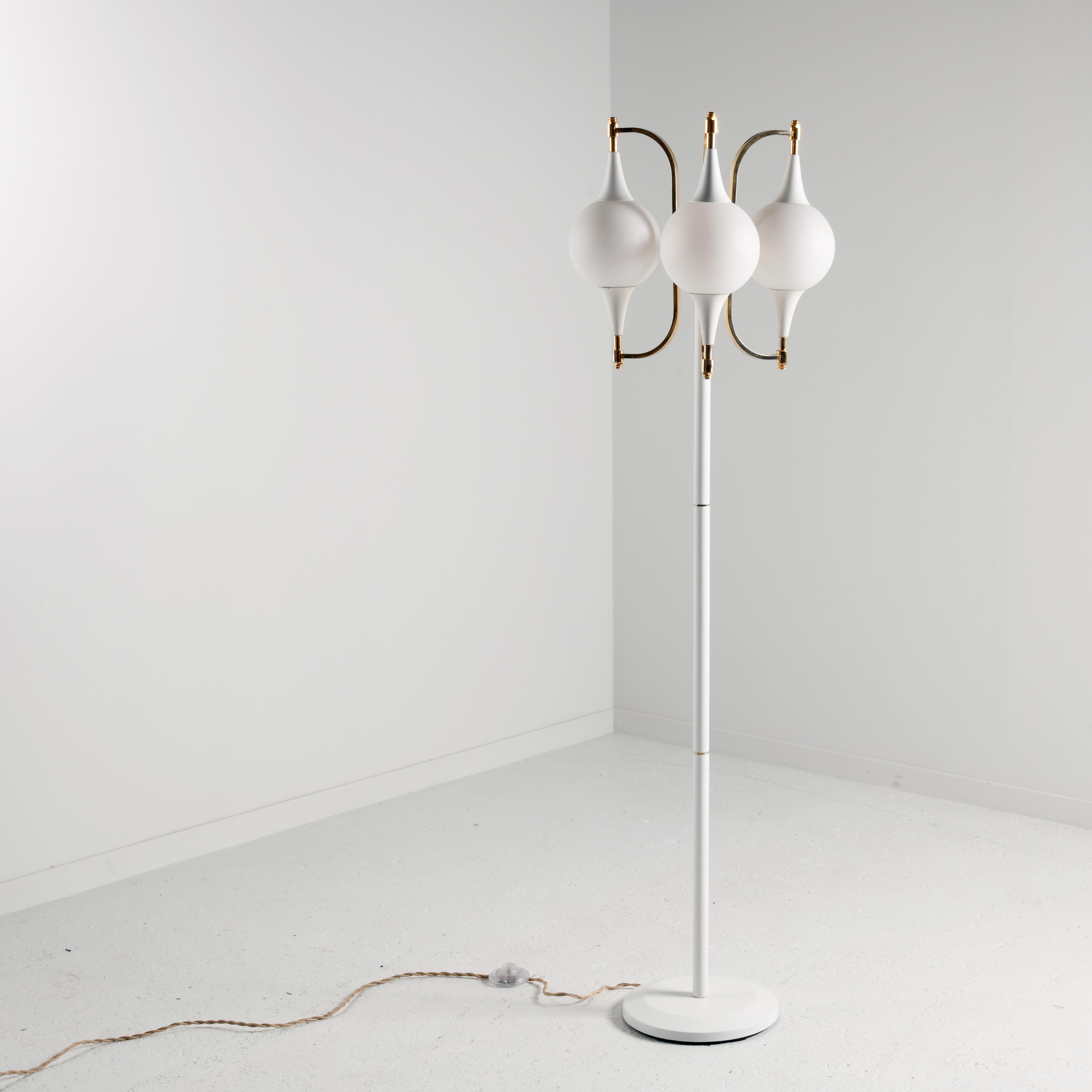 Three-light space age floor lamp in the style of the Italian productions by Stilnovo in the 1970s. The base and shaft are in white lacquered metal, with brass rings, and there is a steel ballast under the base for stability.  The globes are in white