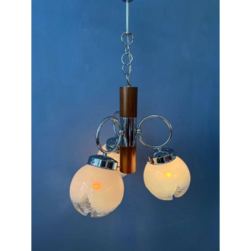 Un lustre classique de Murano par ou dans le style de Murano. La lampe a trois abat-jours en verre et un cadre chromé avec un élément en bois. La lampe nécessite trois ampoules E14.

Dimensions :
ø : 42 cm
Hauteur (lampe seule) : 45 cm

Condit