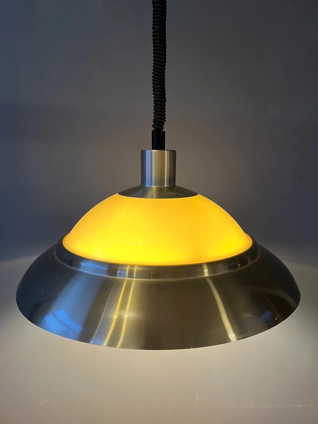 Lampe suspendue vintage Dijkstra datant de l'ère spatiale. La lampe se compose d'une partie en aluminium et d'une partie en plexiglas, ce qui crée une belle diffusion de la lumière. La lampe nécessite une ampoule E27/26 (standard).

Dimensions :
ø
