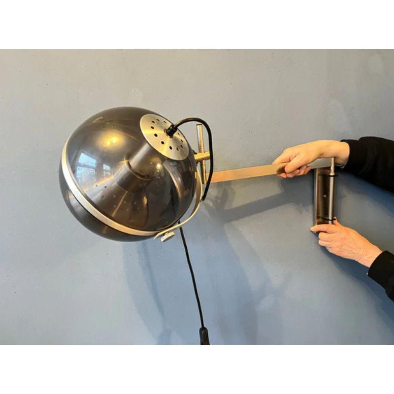 A very rare space age wall lamp from the dutch brand Dijkstra. The transparent outer shade and aluminium inner shade produce a magnificent light in tandem. The shade can be turned in any direction desirable. The lamp requires an E27 lightbulb and