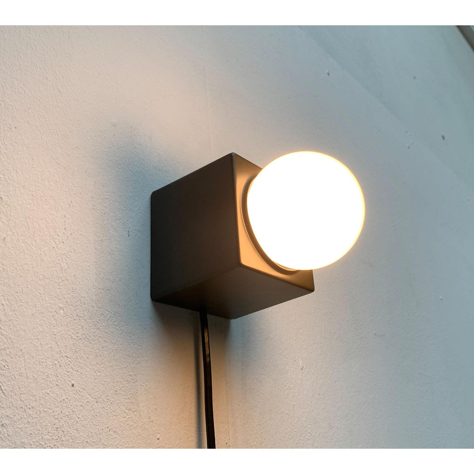 Minimalist table or wall light from philips.

A simple design in cubic form. The actual luminaire body is a cubic base that has a round opening at the top. The version is located inside. The respective lamp protrudes visibly from the base at the top