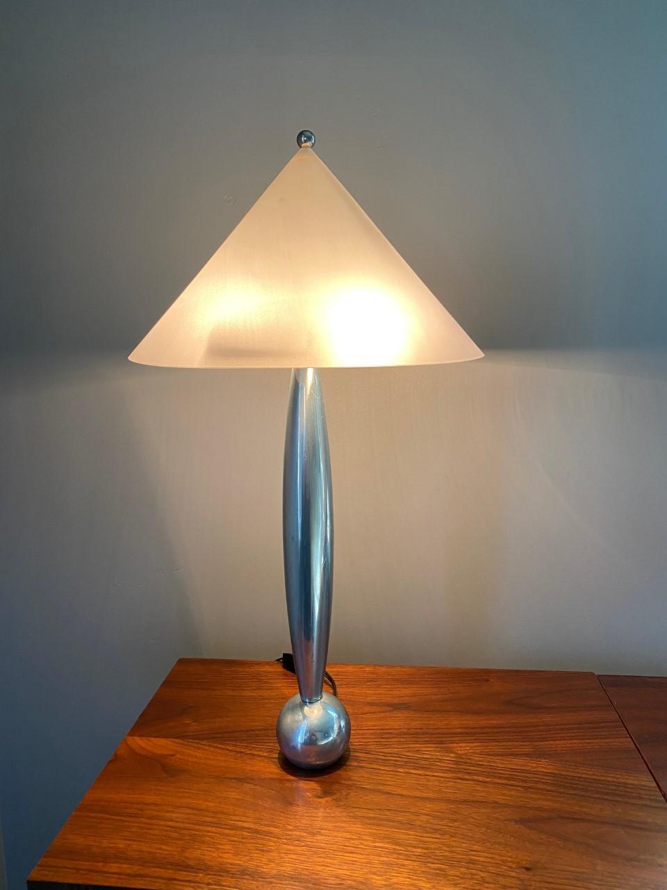 Pair of vintage Space Age cast aluminum table lamps, circa 1970s. A sleek and minimal cast aluminum form with a convex body terminating in a weighted spherical base. Paired with a polymer conical shade. The effect transcends it’s time. The lamp is
