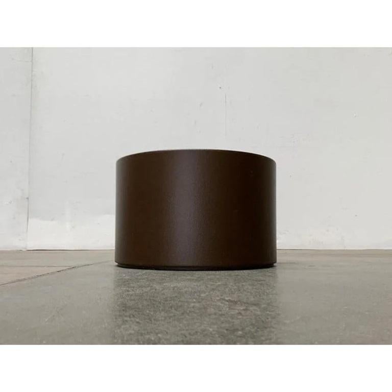 Minimalistischer Space Age-Pflanzkasten aus Kunststoff.

Die runde Dose ist aus Kunststoff gefertigt und dunkelbraun lackiert. Der unterbrochene, untere Rand der Box wirkt wie ein integrierter Sockel, der die Box über eine Schattenfuge vom Boden