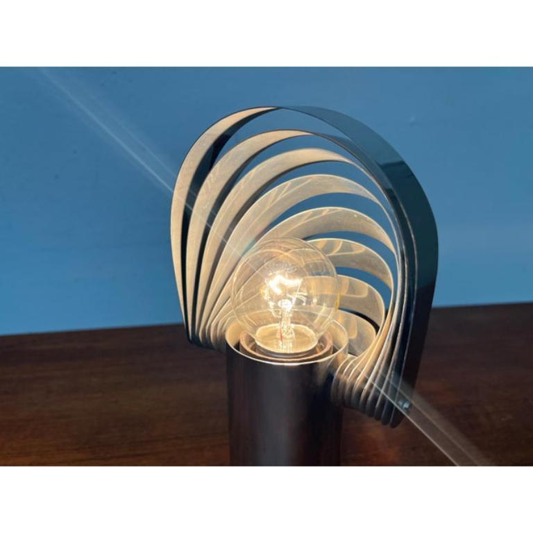 Très rare lampe de table du fabricant suisse Temde basée sur un design d'Eva Renée Nele du début des années 1970.

Le détail le plus frappant de cette lampe se trouve dans le design de la tête de lampe. Des bandes métalliques incurvées entourent la