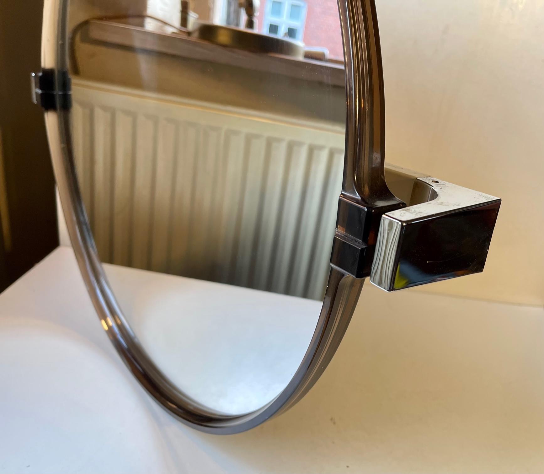 A tilting/adjustable wall mirror in smoked transparent acrylic. Suitable for bathrooms, vanity areas or as a make-up mirror in your bedroom. It was designed and manufactured by Allibert Germany circa 1970-80. Measurements: D: 50 cm (mirror),