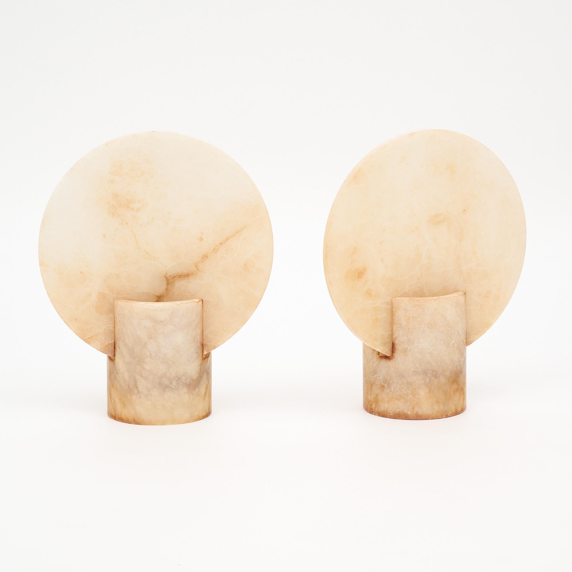 Pair of vintage Spanish lamps made of alabaster. Each features a cylindrical base which holds a round alabaster screen. The light emitted creates a beautiful warm glow. They have been newly wired to fit US standards.