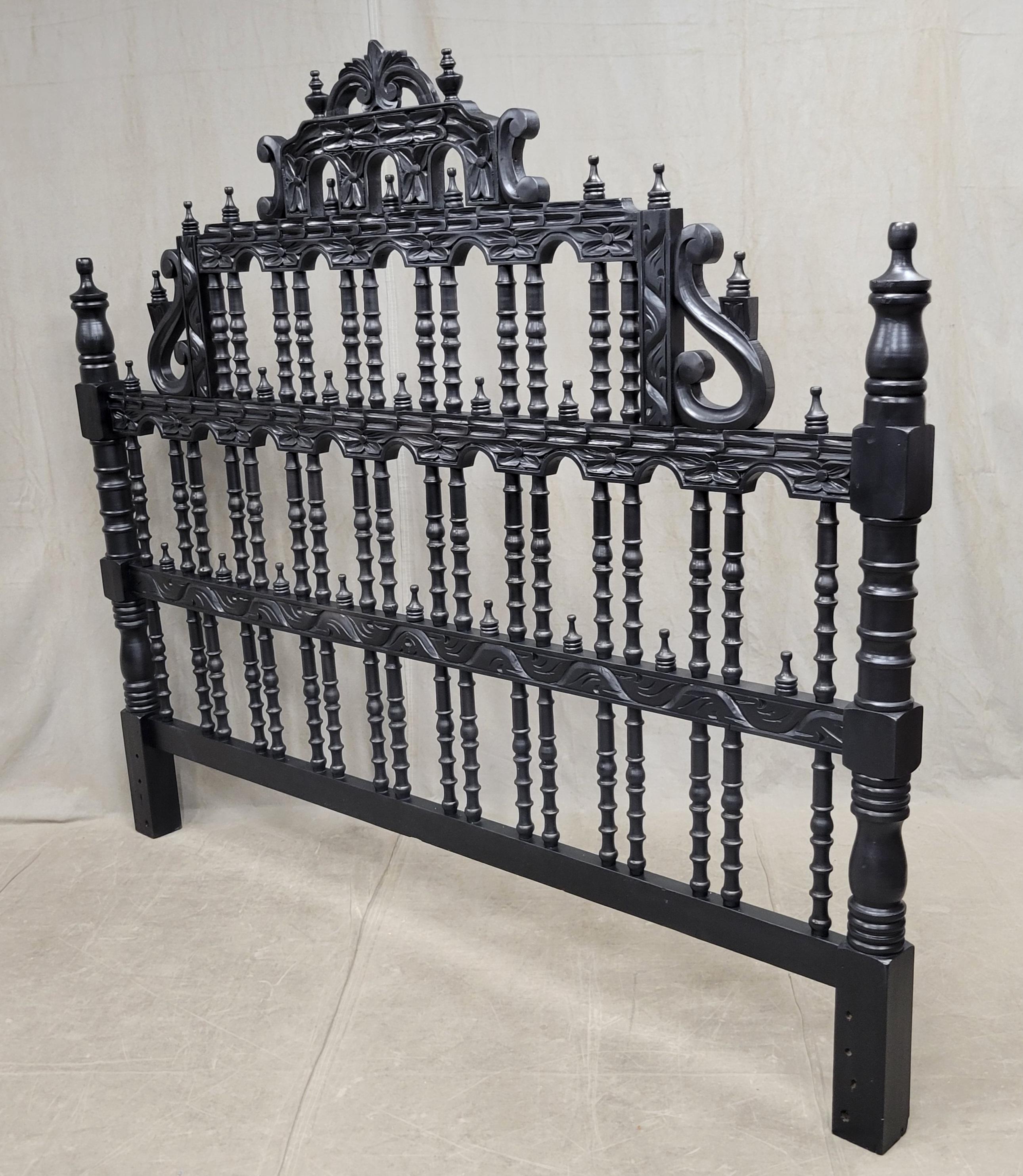 A stunning mid-century Spanish Colonial revival carved wood king size headobard. Beautifully hand carved with turned finials with a black painted finish. In good, stable condition. A small amount of wood bracing has been added to the back side, see