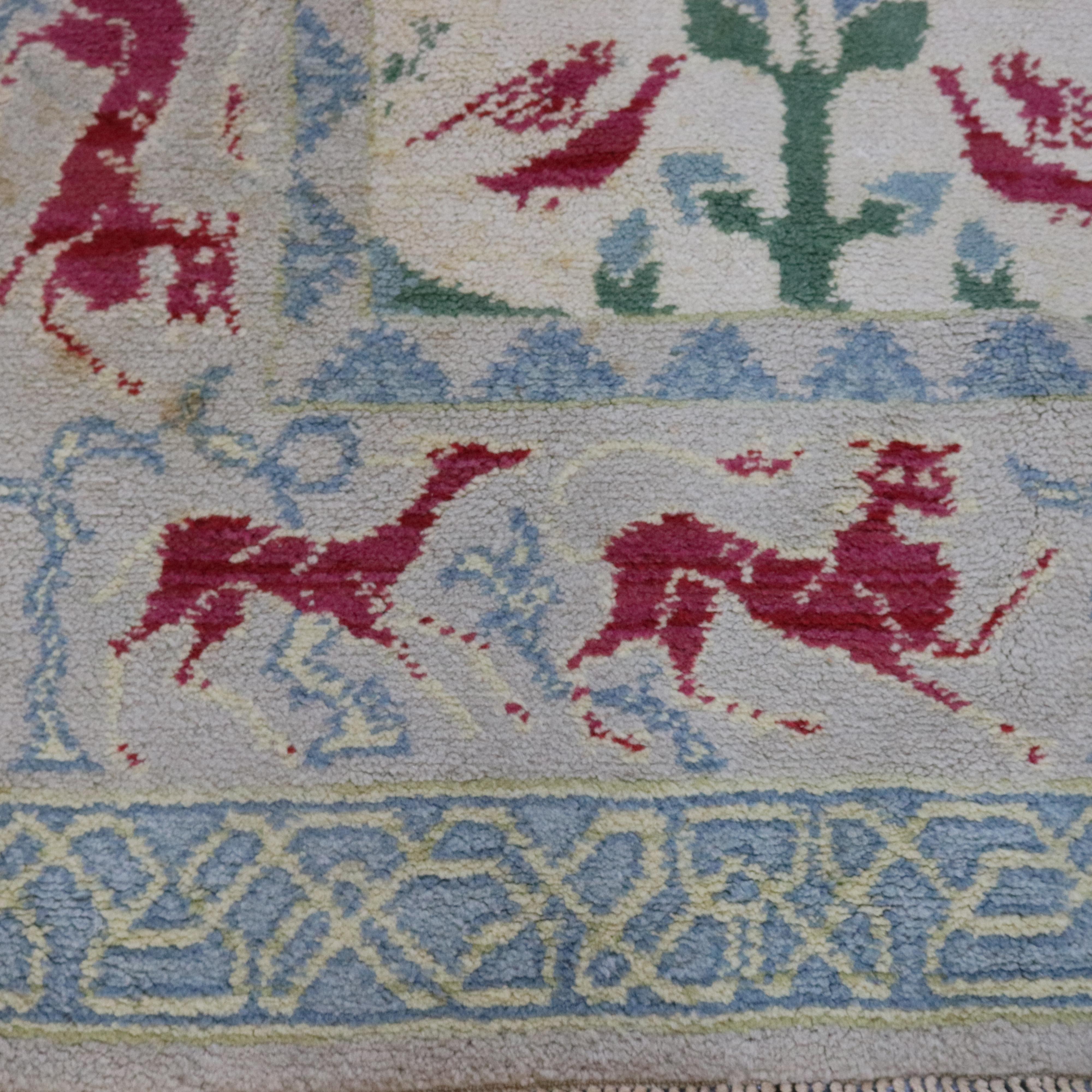 A vintage Spanish room size carpet offers woven wool construction having repeating floral and bird design with border having repeating pattern of animal figure hunt scene, en verso label reads 