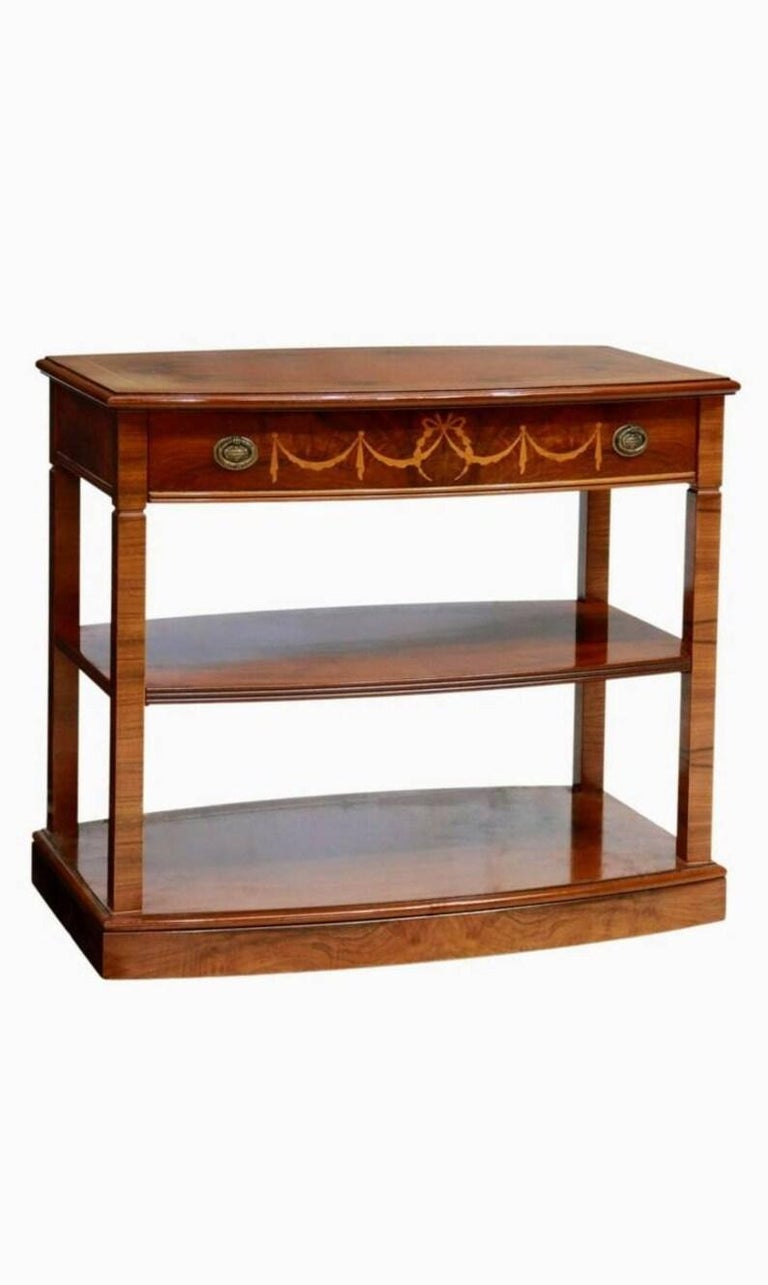 A vintage Spanish tiered service table from the mid-20th century. Featuring warm, richly figured walnut, having a shaped top with book-matched burlwood framed by contrasting string banding inlay, over a single bow front drawer with Neo-classical