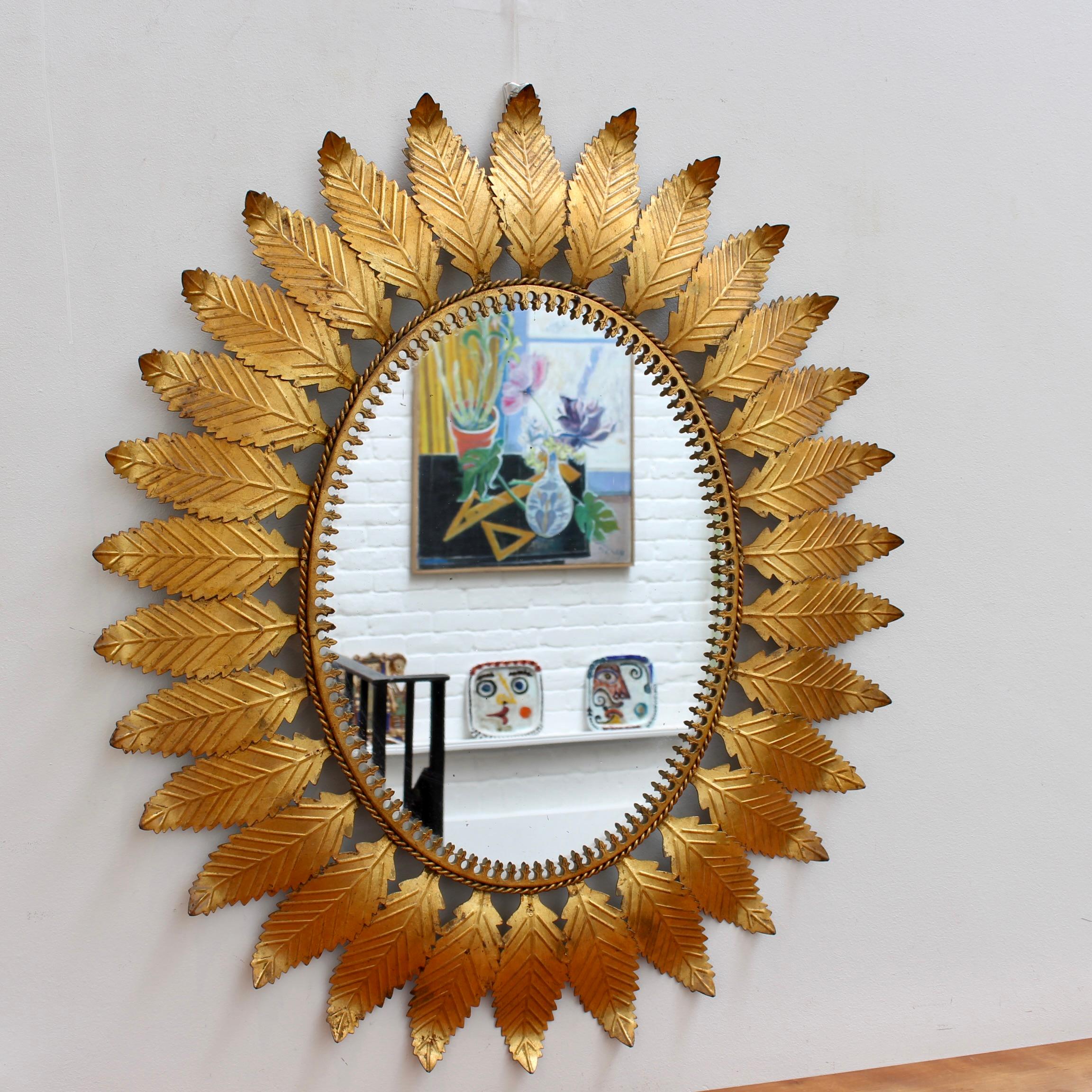 Spanish gilt metal sunburst mirror (circa 1970s) with leaf motif rays and a repeating pattern of rope bordering the glass. The lustrous frame is in overall good condition with lovely golden highlights - there are some small spots on the mirror