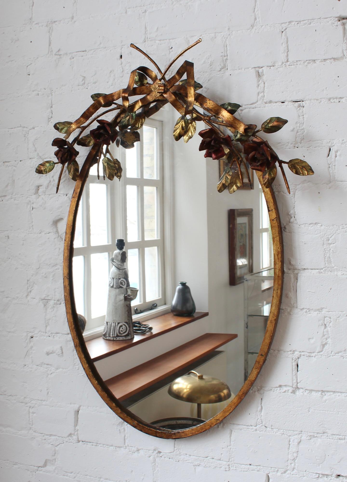 Vintage Spanish gilt metal toleware wall mirror (circa 1970s). The Spanish excel at making beautiful toleware pieces which are decoratively painted and gilded enamelled metal ware. This gorgeous mirror is topped by a toleware flower and ribbon