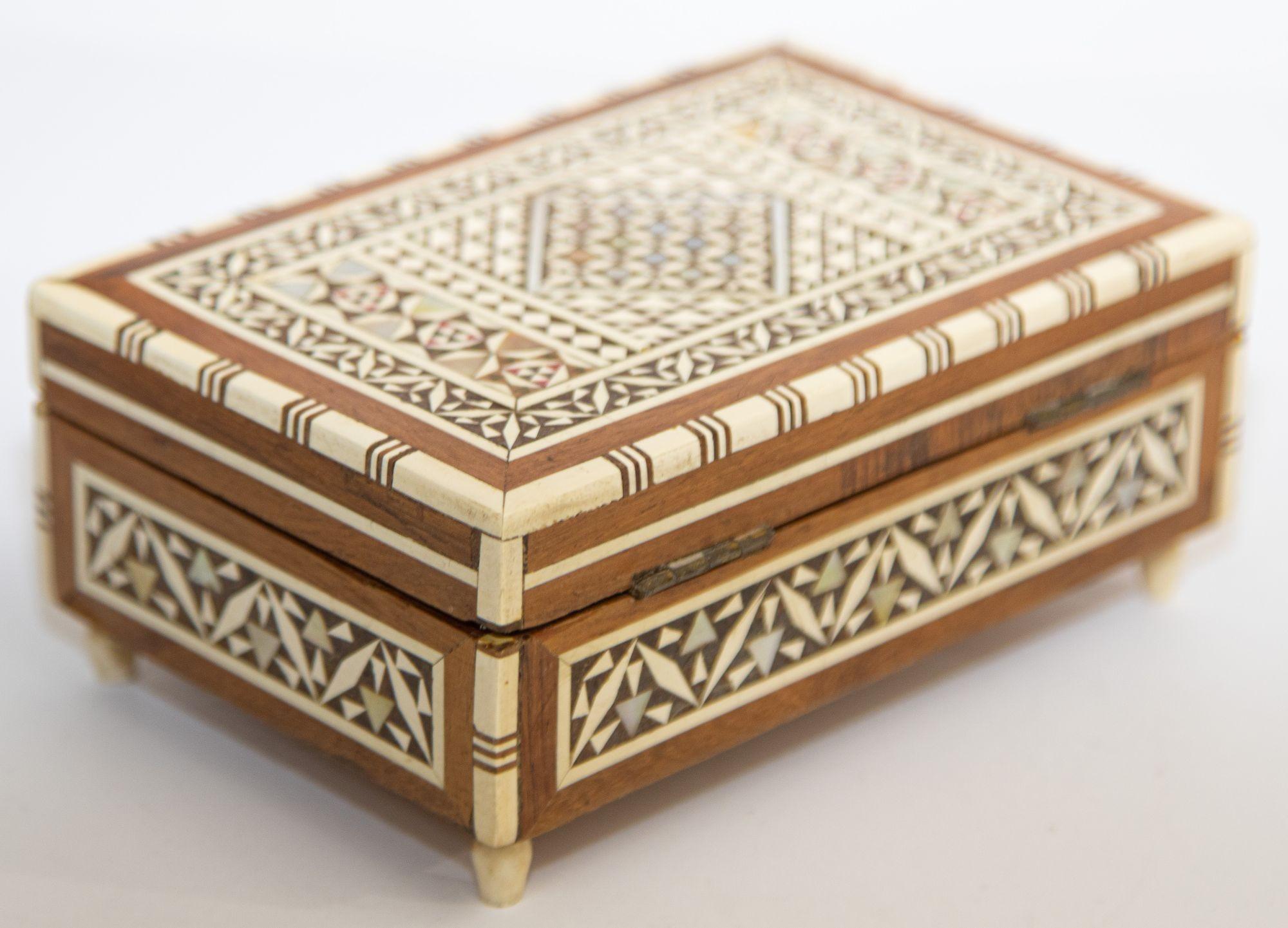 Vintage Spanish Granada Intarsien Einlegearbeit Dekorative Spieldose mit weißem Knochen eingelegt.
Es ist aufwendig gestaltet mit einem Sadeli-Mosaik im syrischen Stil, gebeiztem Kiefernholz, fein eingelegt in islamisch-maurische geometrische