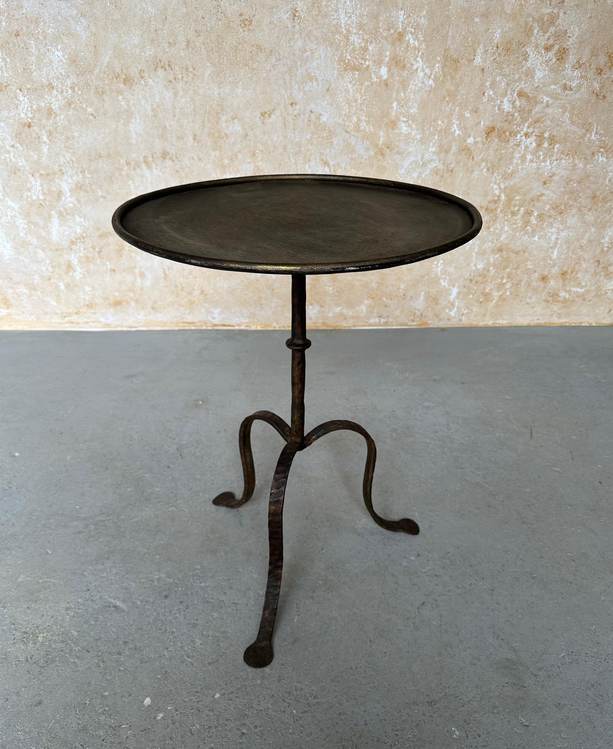 This large rustic Spanish iron side table from the 1950s features a circular stem with a central ring detail supported by a tripod base with gracefully curved hammered legs. The round top, surrounded by a rolled frame, is designed to securely hold