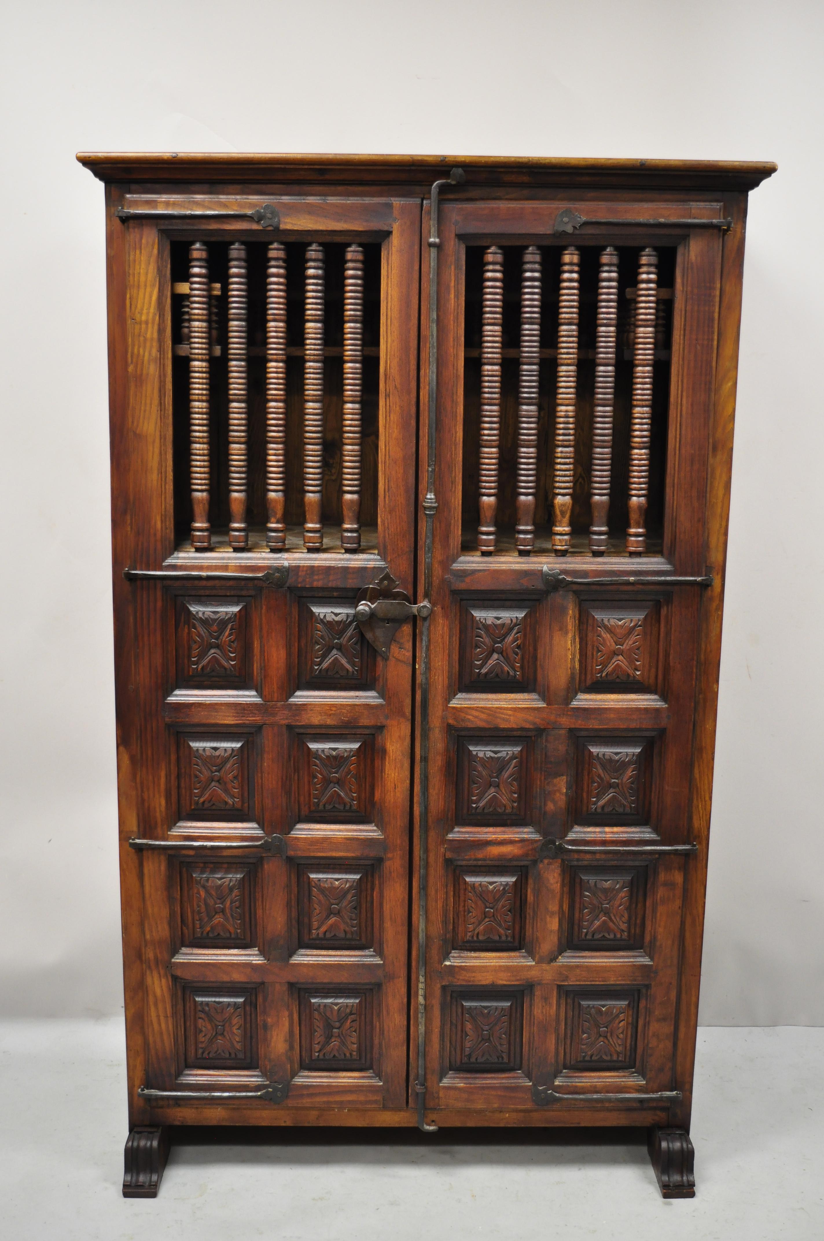 Vintage Spanish Renaissance carved wood cabinet cupboard with raised panel spindle carvings. Item features (2) hidden side drawers, cast iron hardware, carved panel front and sides, solid wood construction, beautiful wood grain, nicely carved