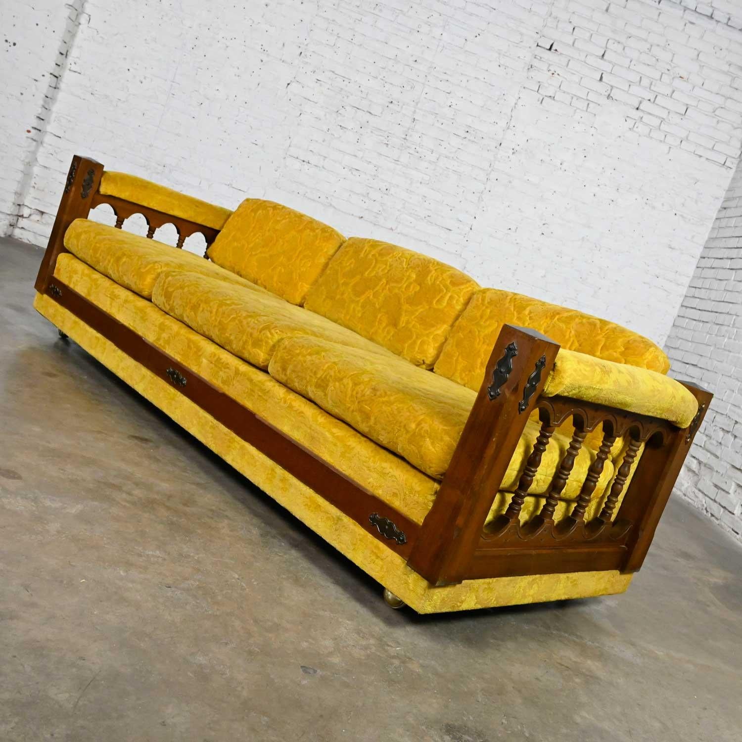 Stunning vintage Spanish Revival sofa with velvety gold textured fabric, a dark stained wood frame with turned spindle sides, dark brass details, round tapered wood back legs & front brass ball casters. Beautiful condition, keeping in mind that this