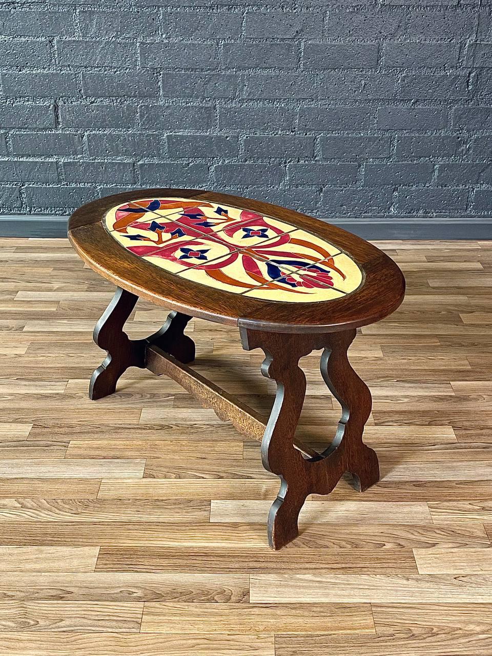 Zustand: Original Vintage By Zustand

MATERIALIEN: Nussbaum-gepflegte Eiche, dekorative Fliesenintarsien

Dieser Couchtisch aus Eichenholz und Fliesen im spanischen Revival-Stil aus den 1940er Jahren zeigt die reiche Handwerkskunst und dekorative