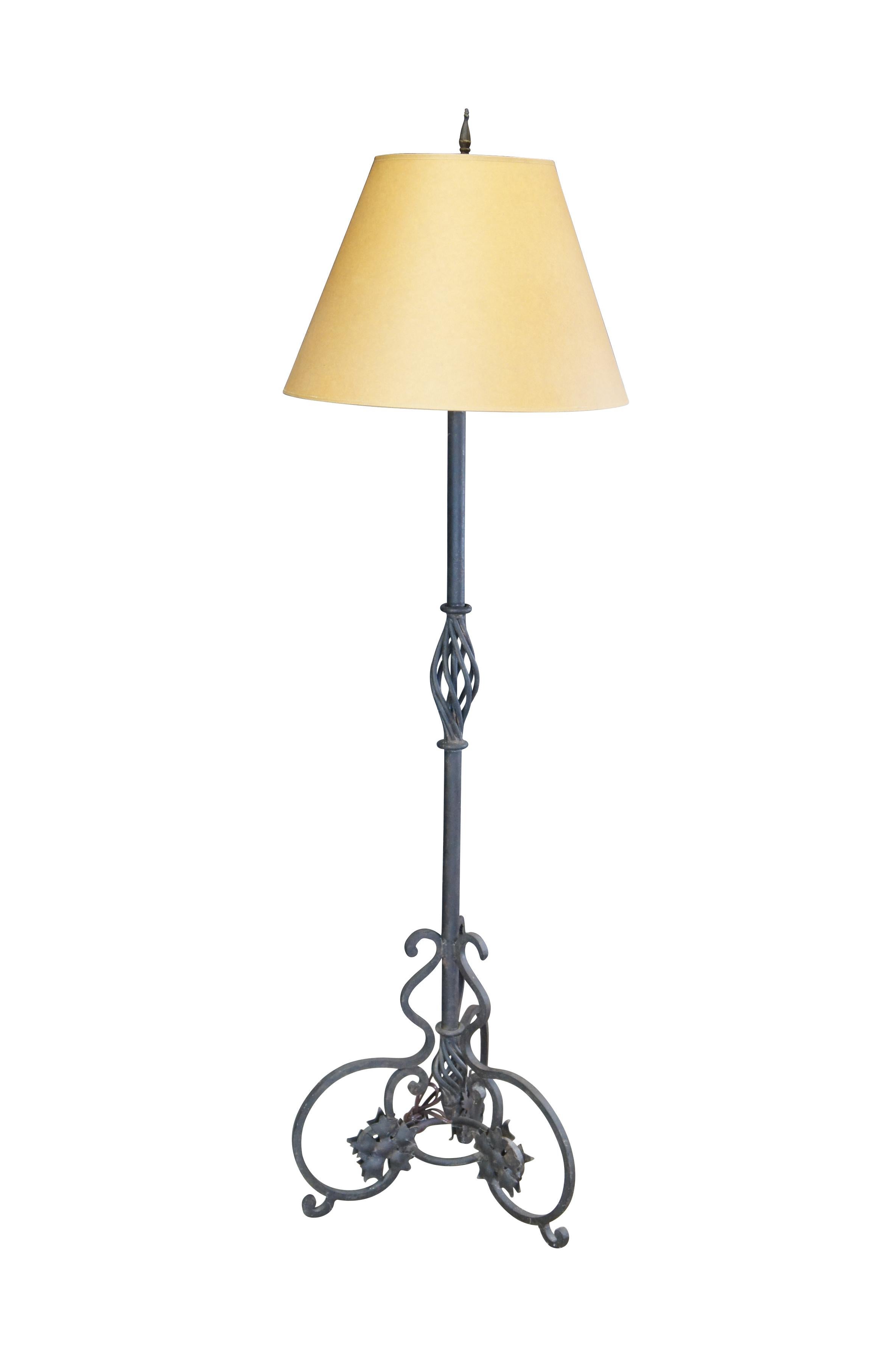 Late 20th Century Spanish Mediterranean ornate wrought iron floor lamp, will candlestick topper and drip pan.  Features a tripod base with scrolled accents and open twisted column at the center.  The base is accented by 5 petal florets. Includes