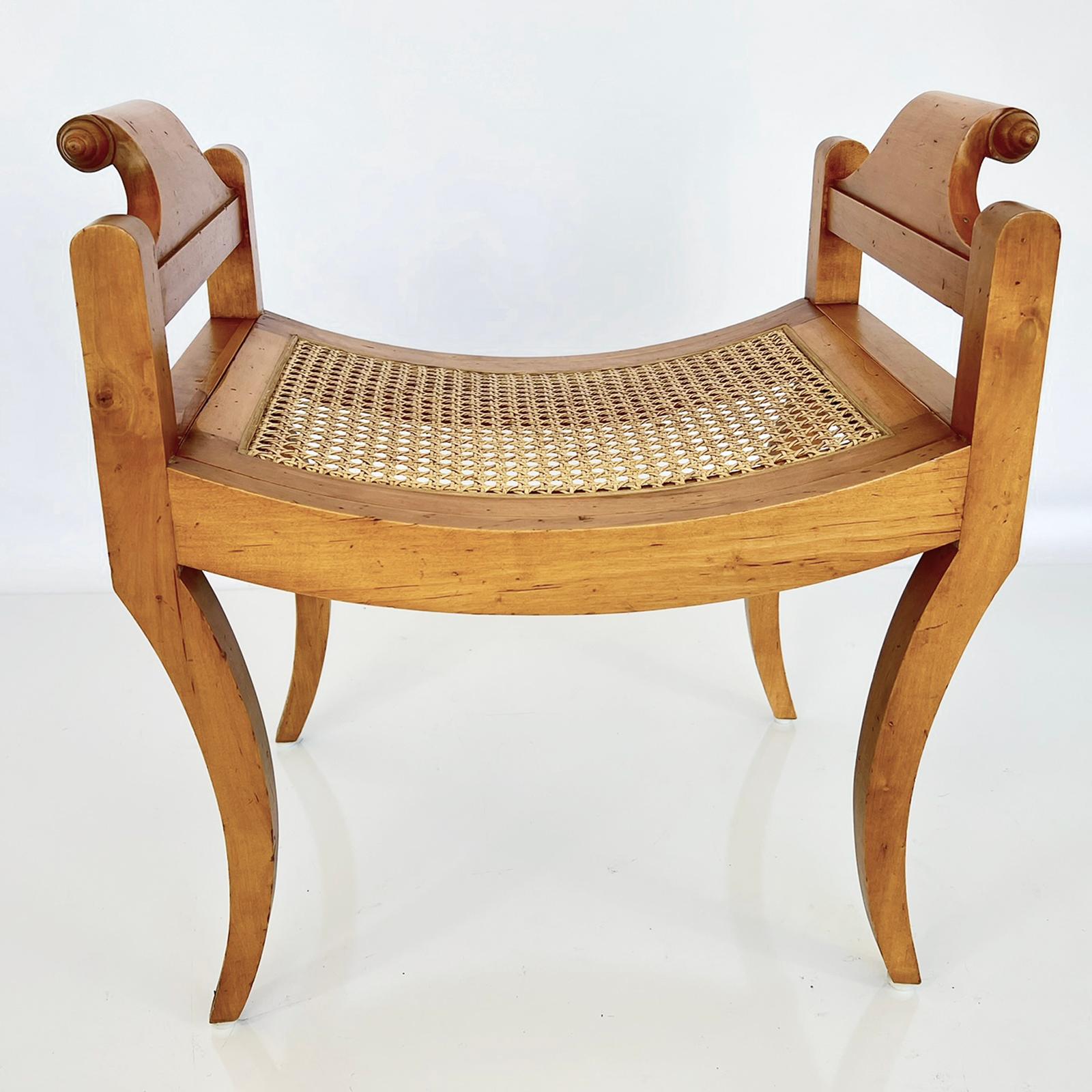 Bench, of satinwood, having a caned seat flanked by outscrolled arms ending in spiral handles, raised on bowed apron, on four sabre legs. 

Stock ID: D1503.