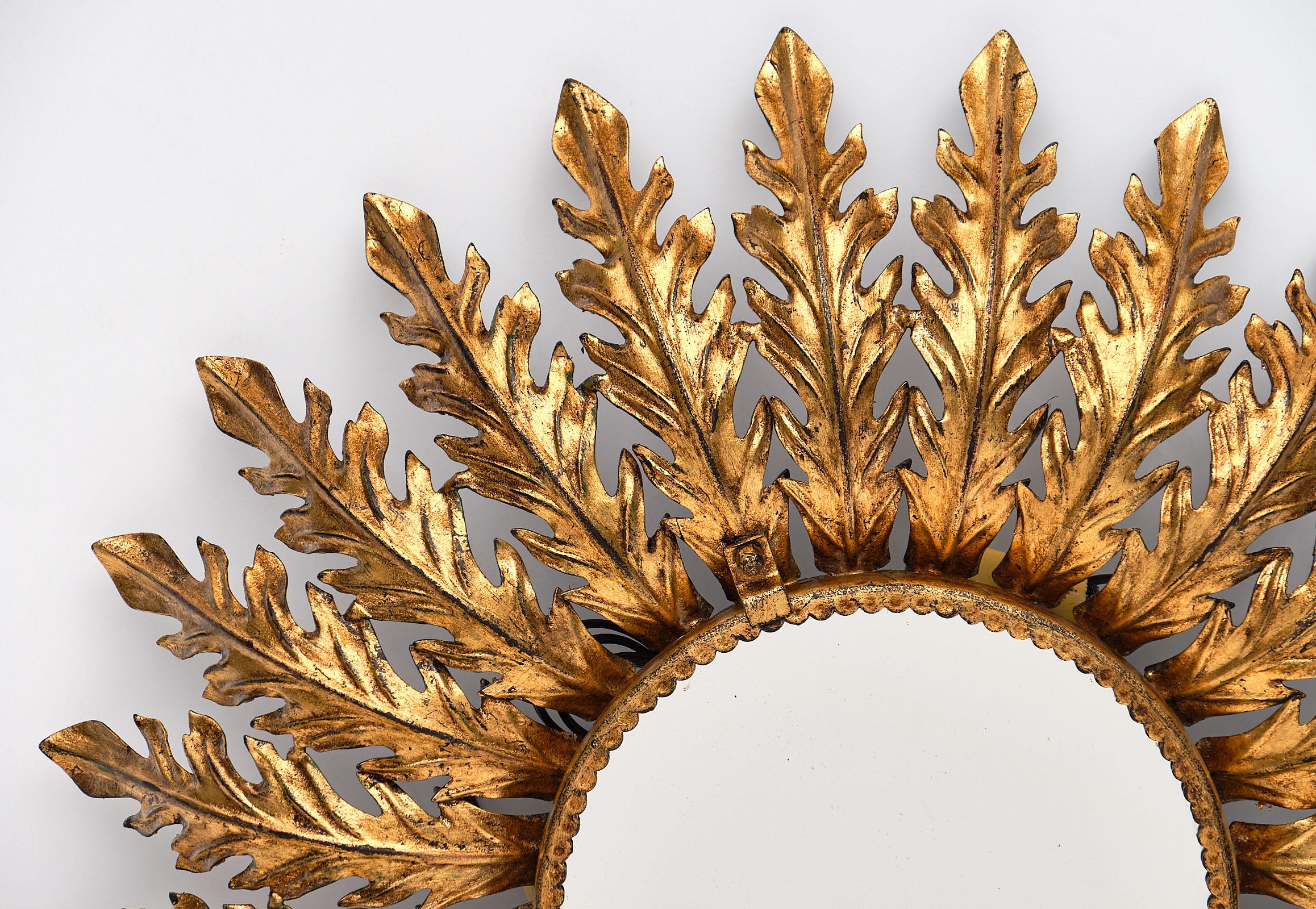 Spanish vintage sunburst mirror with backlight featuring gold leafed embossed tole rays adorning a circular central mirror. The backlight gives this piece a beautiful glow. It has been newly wired to fit US standards.