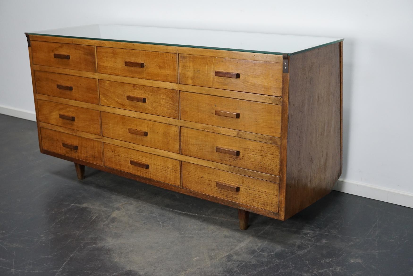 This vintage haberdashery shop counter dates from the 1960s and was made in Spain. It features a wooden frame, glass casing and drawers in walnut with hardwood handles.